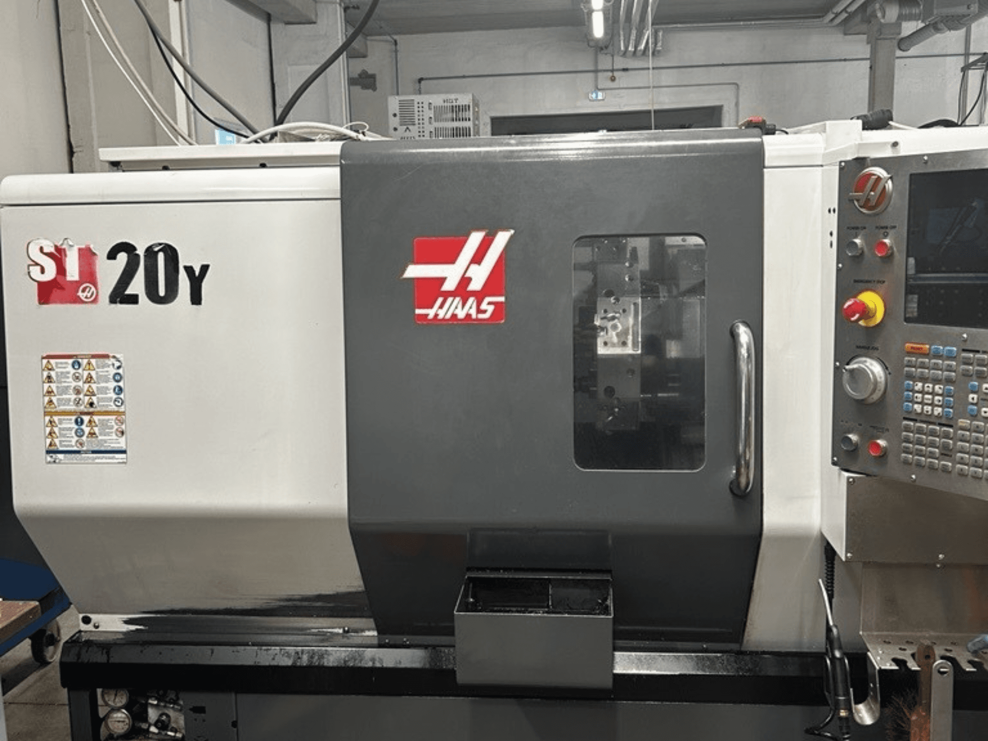 Tornio CNC Haas ST-20Y, vista frontale, con pannello di controllo, etichette di sicurezza e finestra operativa.