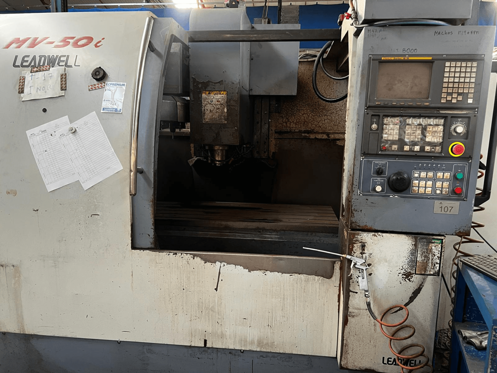 Centro di lavorazione verticale Leadwell MV-50i, vista frontale, che mostra il pannello di controllo, l'area del mandrino e il piano di lavoro con segni di usura.