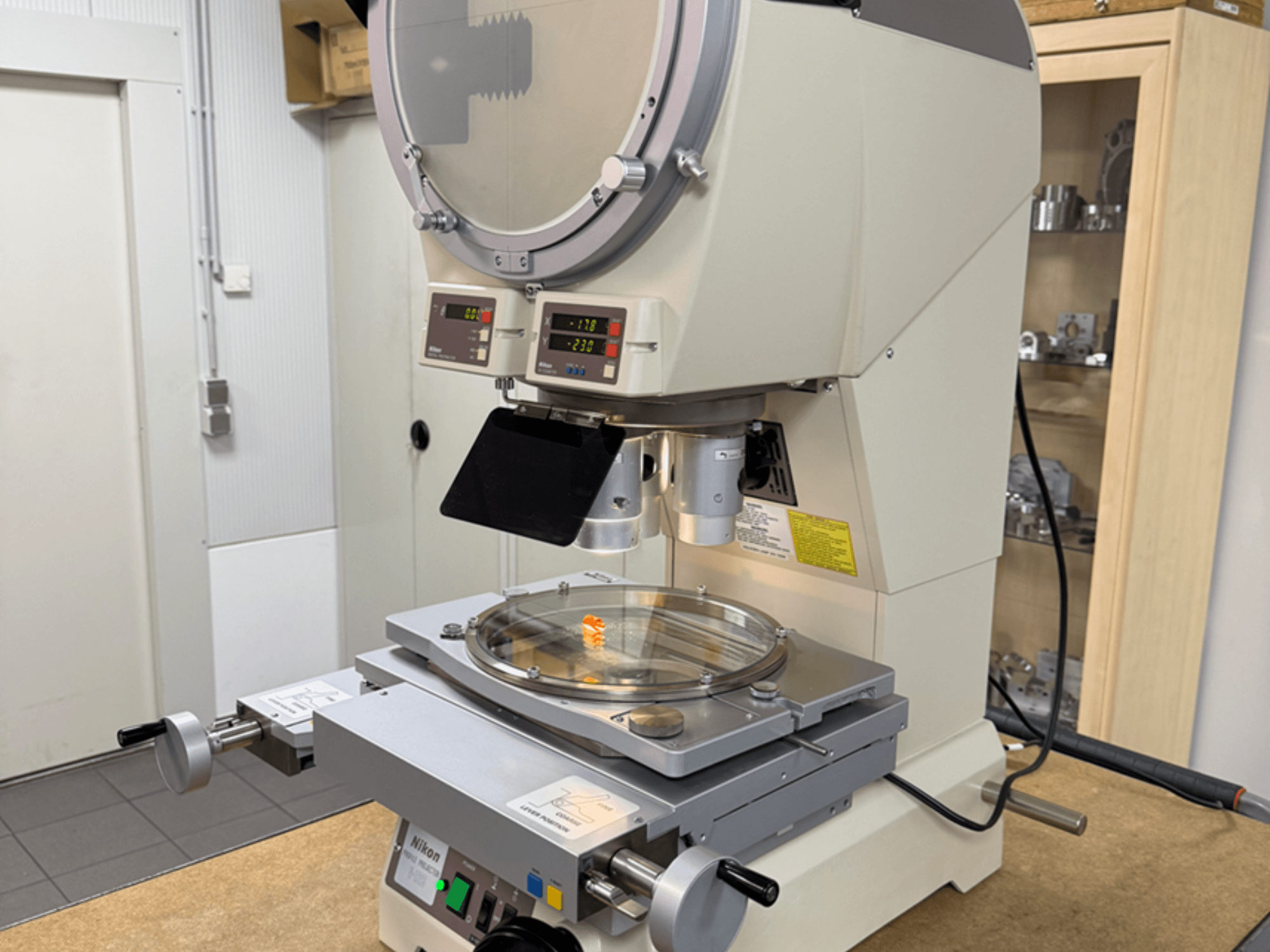 Microscopio modello Nikon con vista frontale, dotato di display digitale, palcoscenico regolabile e piastra di vetro circolare.