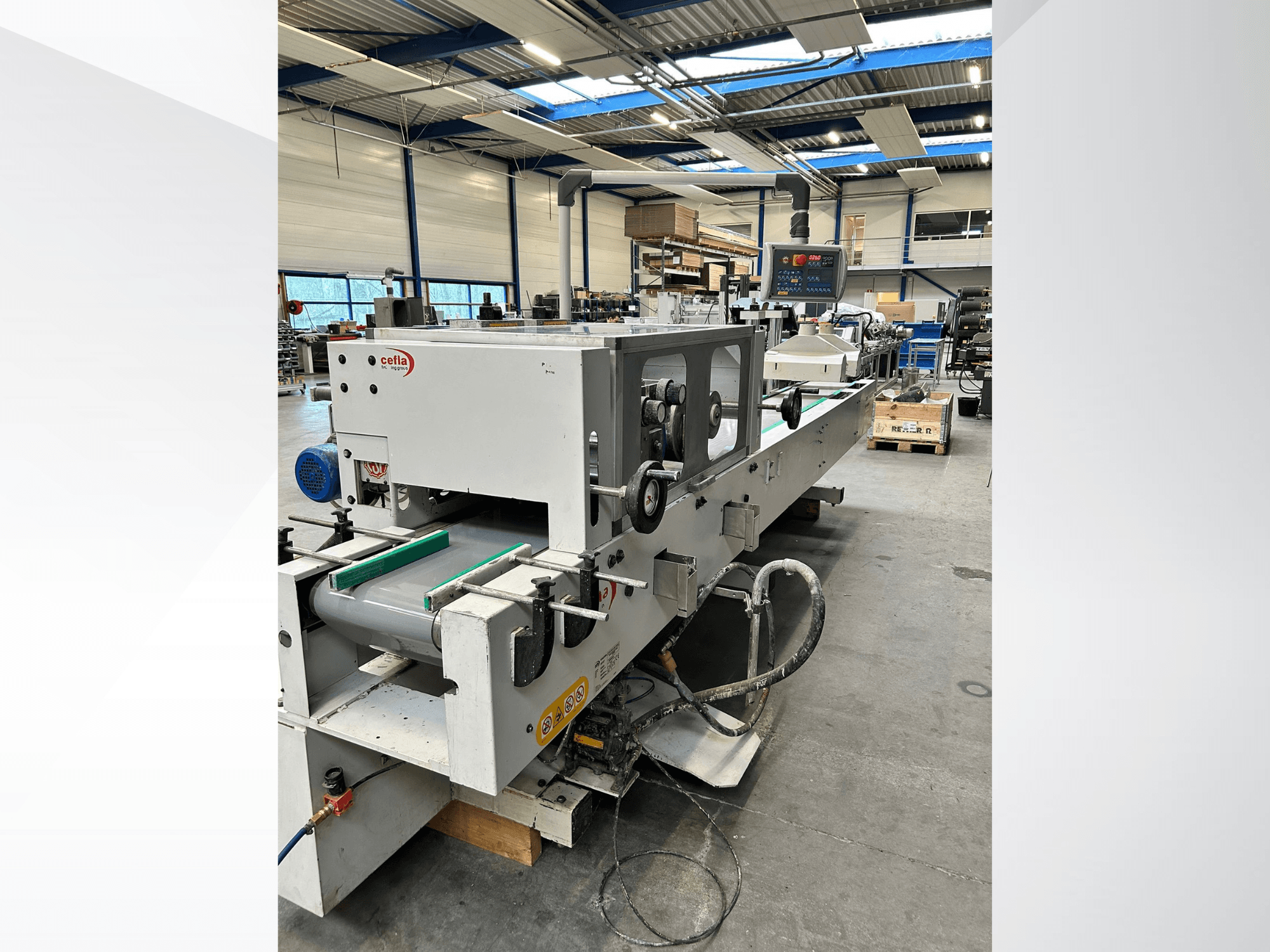 Vista frontale della macchina per la lavorazione del legno CEFLA Smartparquet MRF-2VS/300, con in primo piano il pannello di controllo e il nastro trasportatore dotato di rulli verdi.