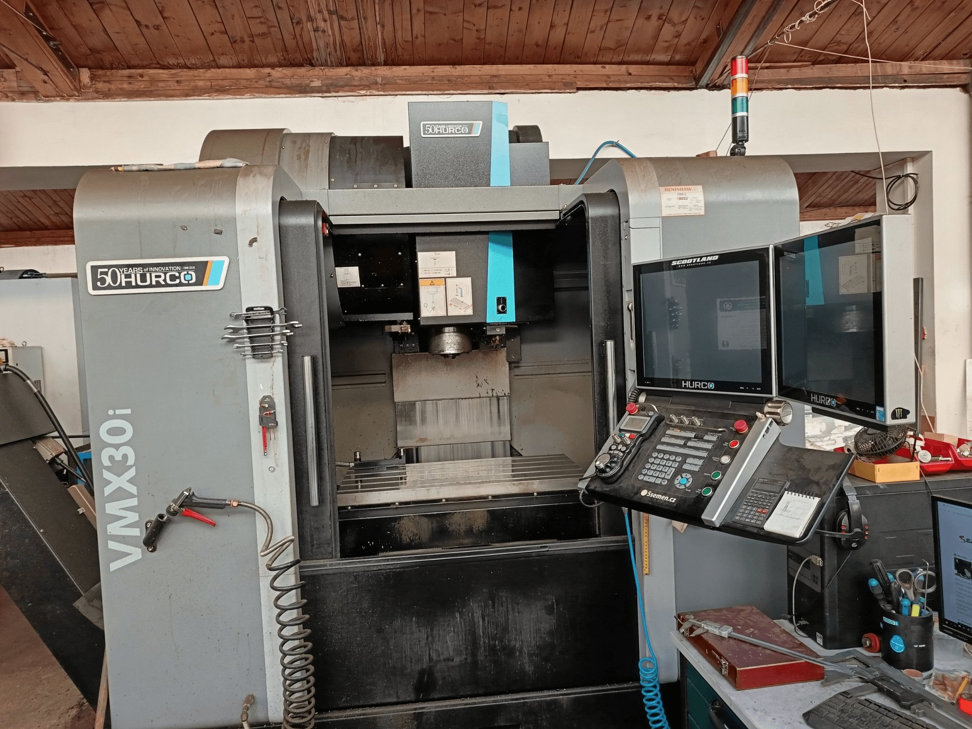 Fresatrice CNC Hurco VMX30i in vista frontale, con doppio monitor, pannello di controllo e tubo flessibile collegato.