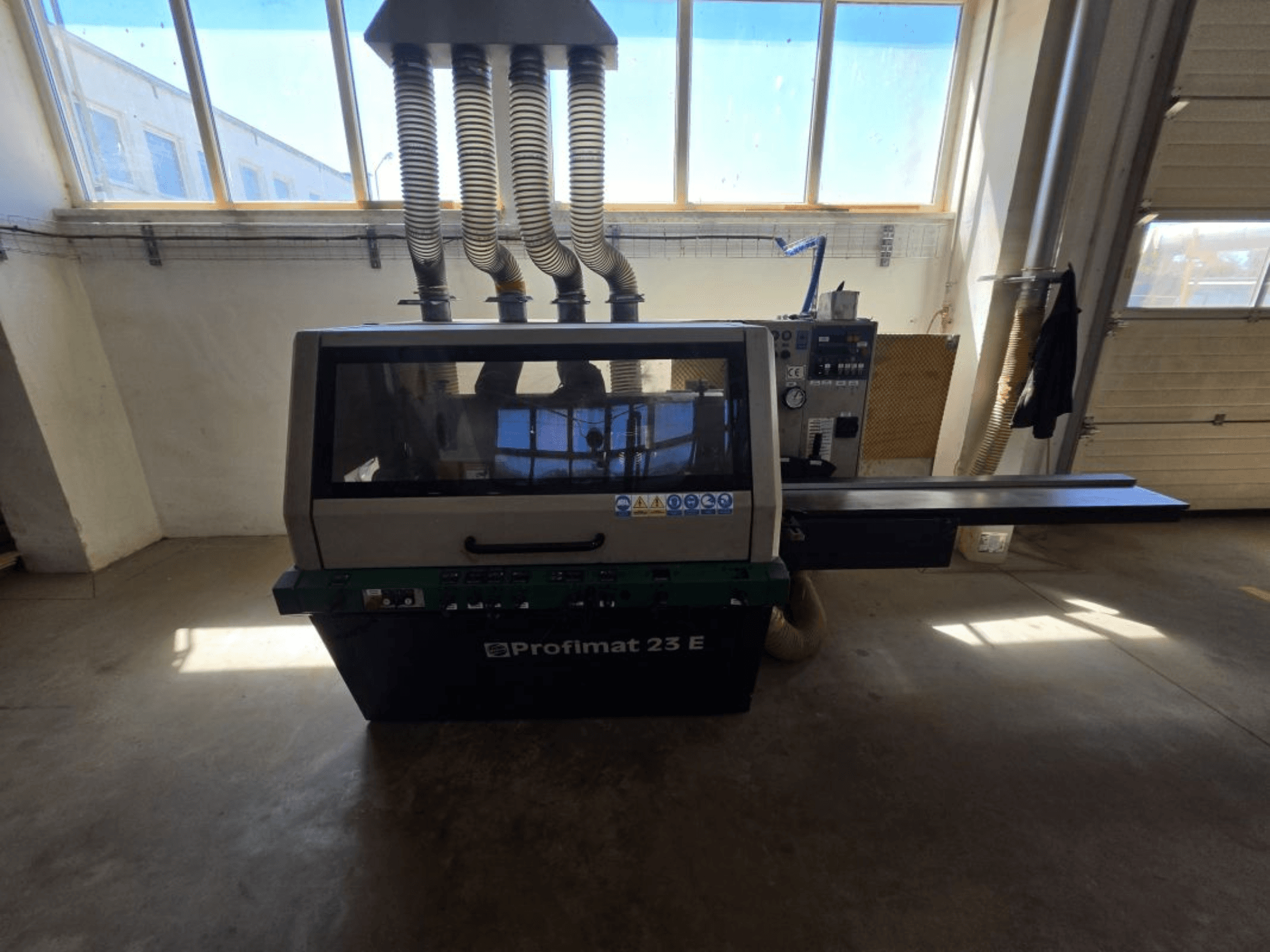 Pialla per legno WEINIG DIMTER PROFIMAT 23 E, vista frontale, con pannello di controllo e tubi di aspirazione visibili, in un'officina.