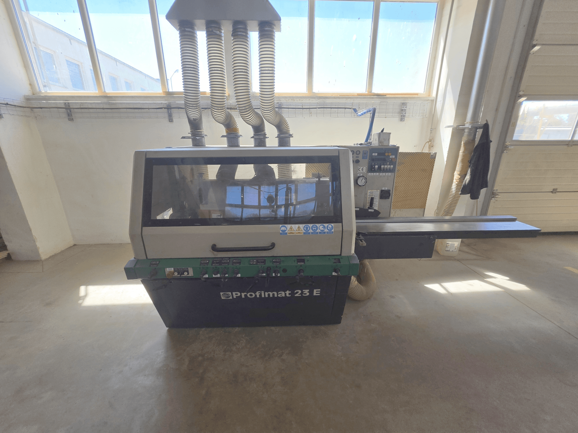 Pialla per legno WEINIG DIMTER PROFIMAT 23 E, vista frontale, con pannello di controllo, piano di alimentazione e tubi di aspirazione.