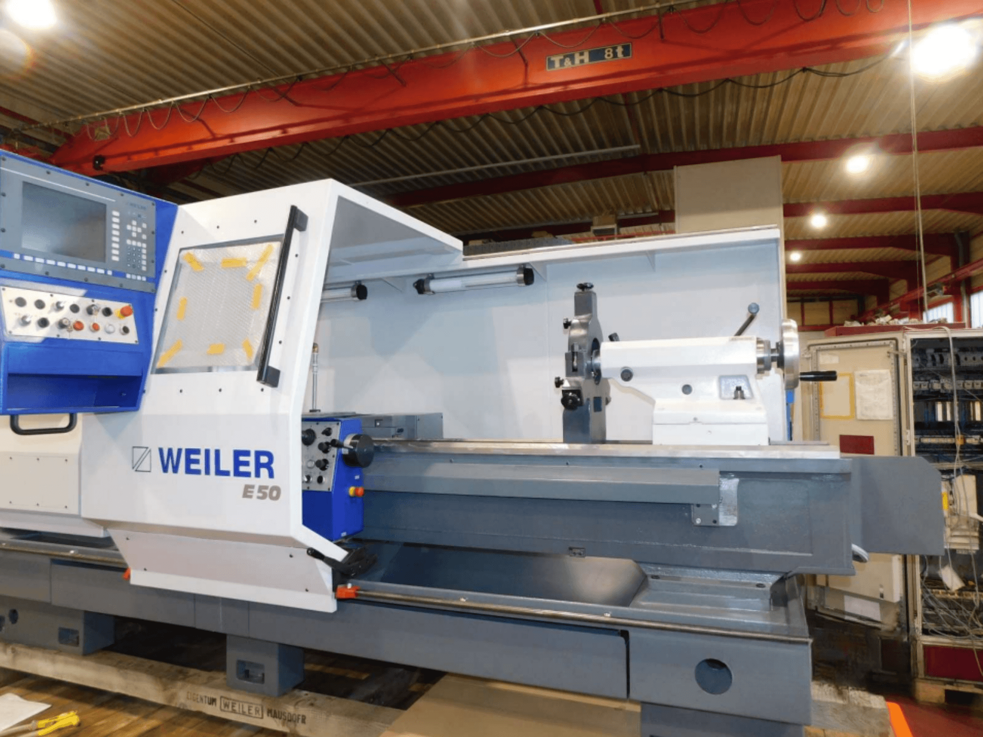Tornio orizzontale Weiler E50, vista frontale, con pannello di controllo, mandrino e tavola di precisione con accessori.