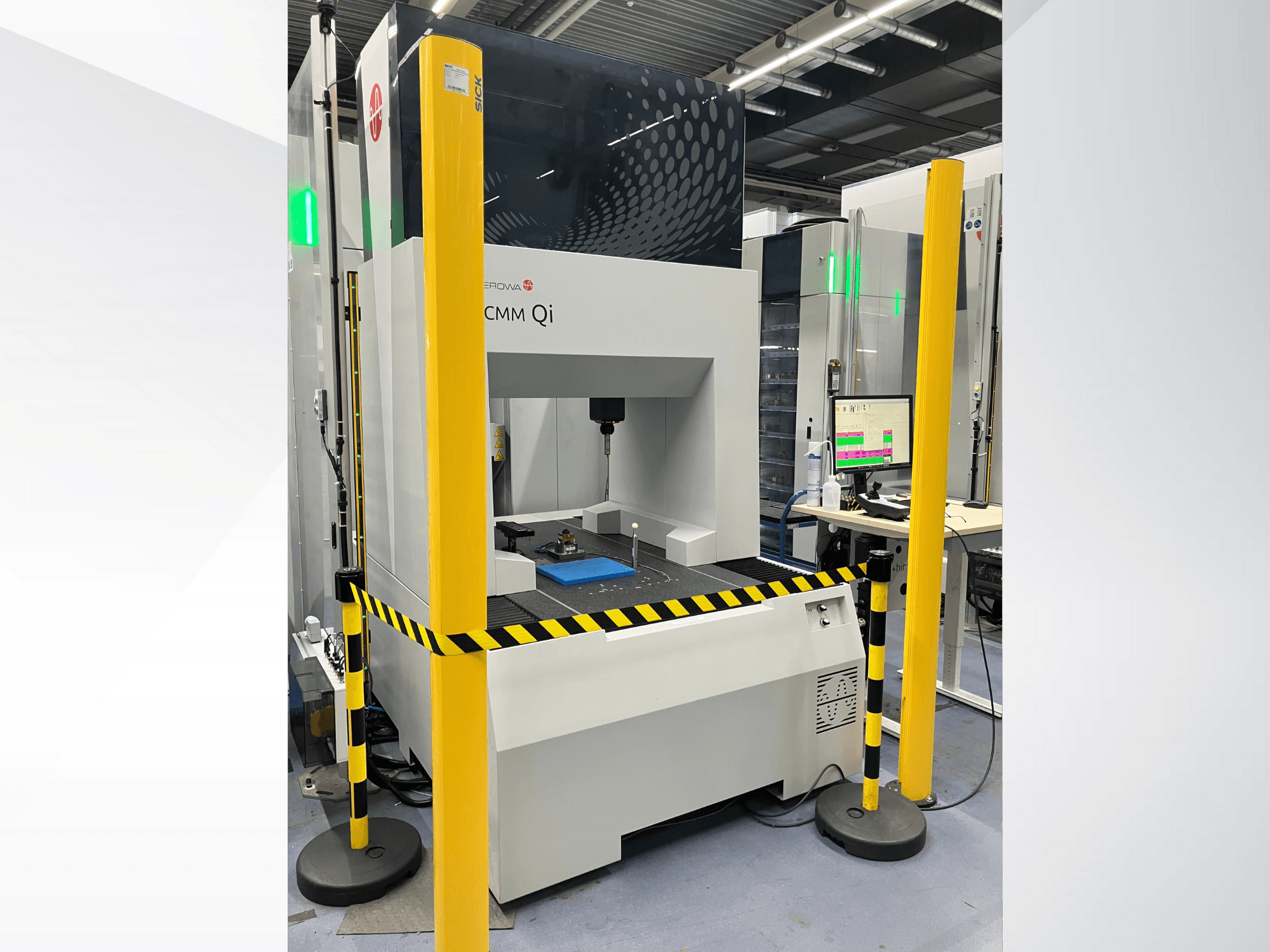 Macchina di misura a coordinate CMM Qi di Aerovent, vista frontale con barriere di sicurezza e monitor che visualizza i dati di misura.