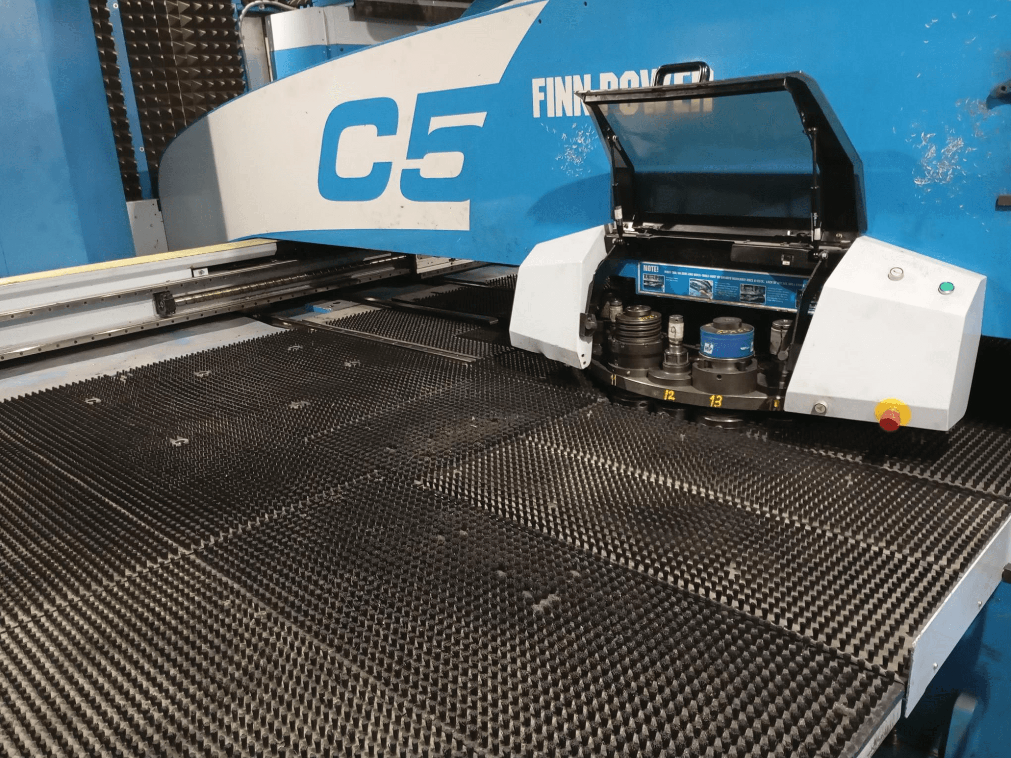 Punzonatrice Finn-Power C5, vista frontale, che mostra la testa dell'utensile aperta su una tavola di lavoro strutturata con punti di indicizzazione numerati.