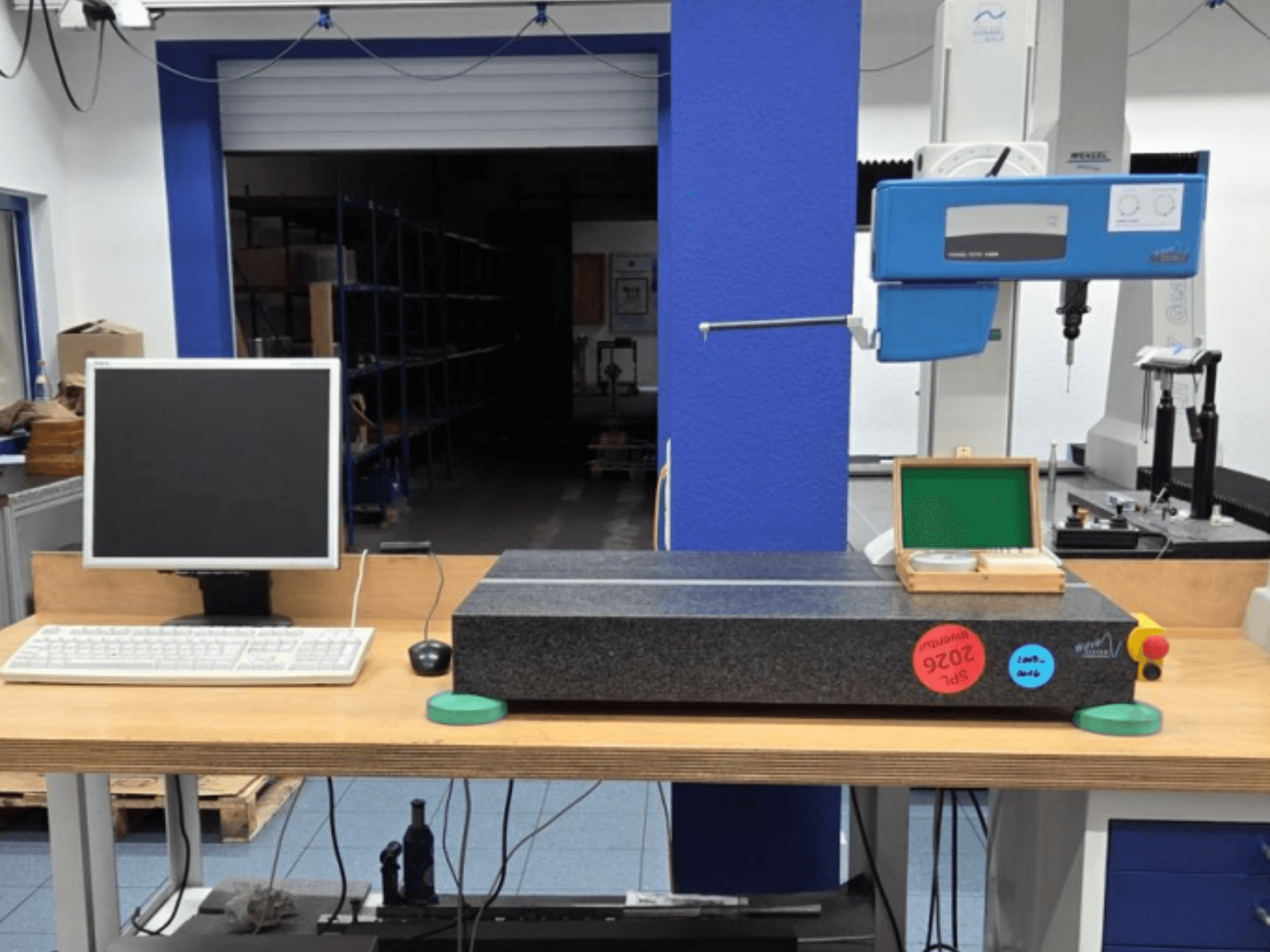 CMM JENOPTIK wave C8000 in un'officina, con monitor, tastiera e superficie di misura in granito. Vista frontale.