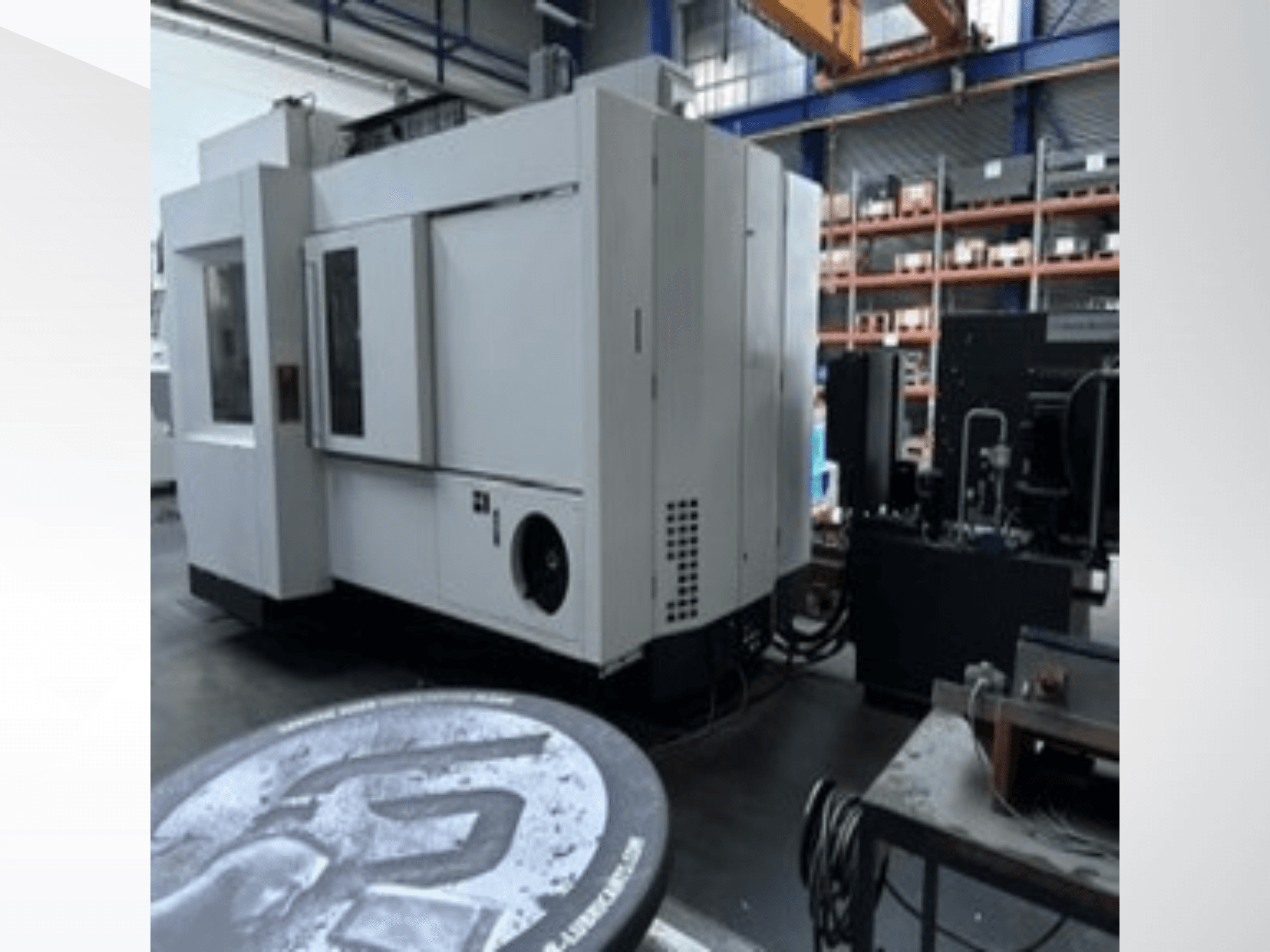 Centro di lavorazione universale MIKRON HPM 1350 U bianco in un'officina; vista laterale che mostra l'ampio pannello di controllo e l'ambiente industriale.
