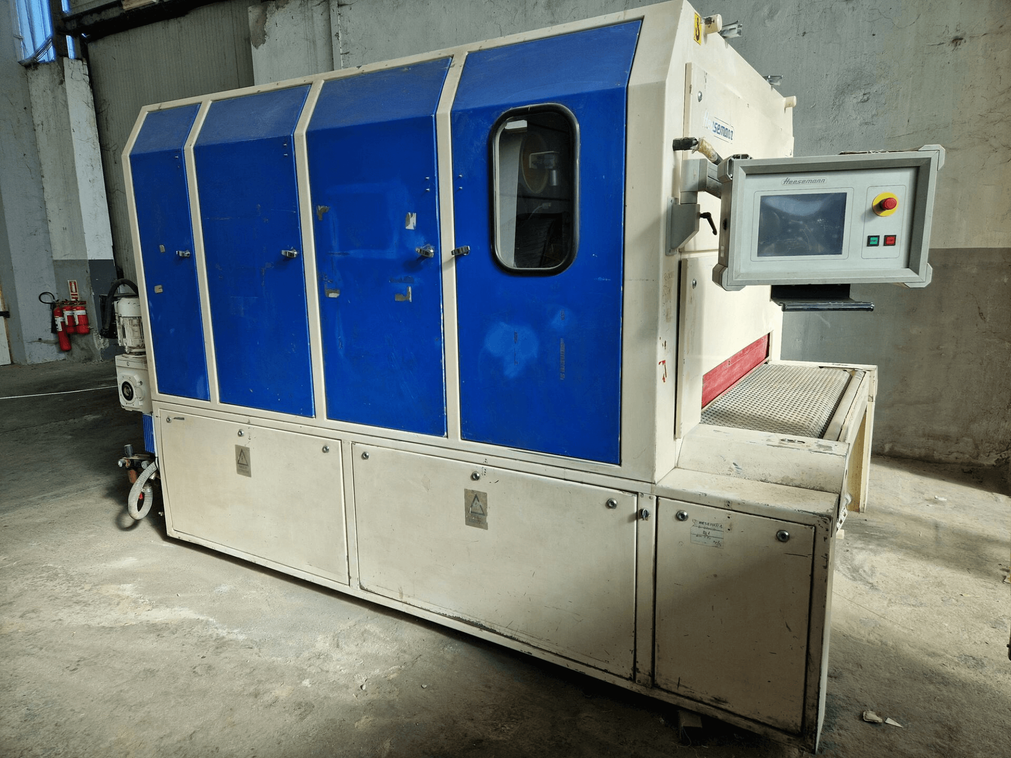 Macchina industriale del marchio "Sedecom", vista laterale; presenta pannelli blu, uno schermo di controllo e una superficie strutturata per la movimentazione dei prodotti.