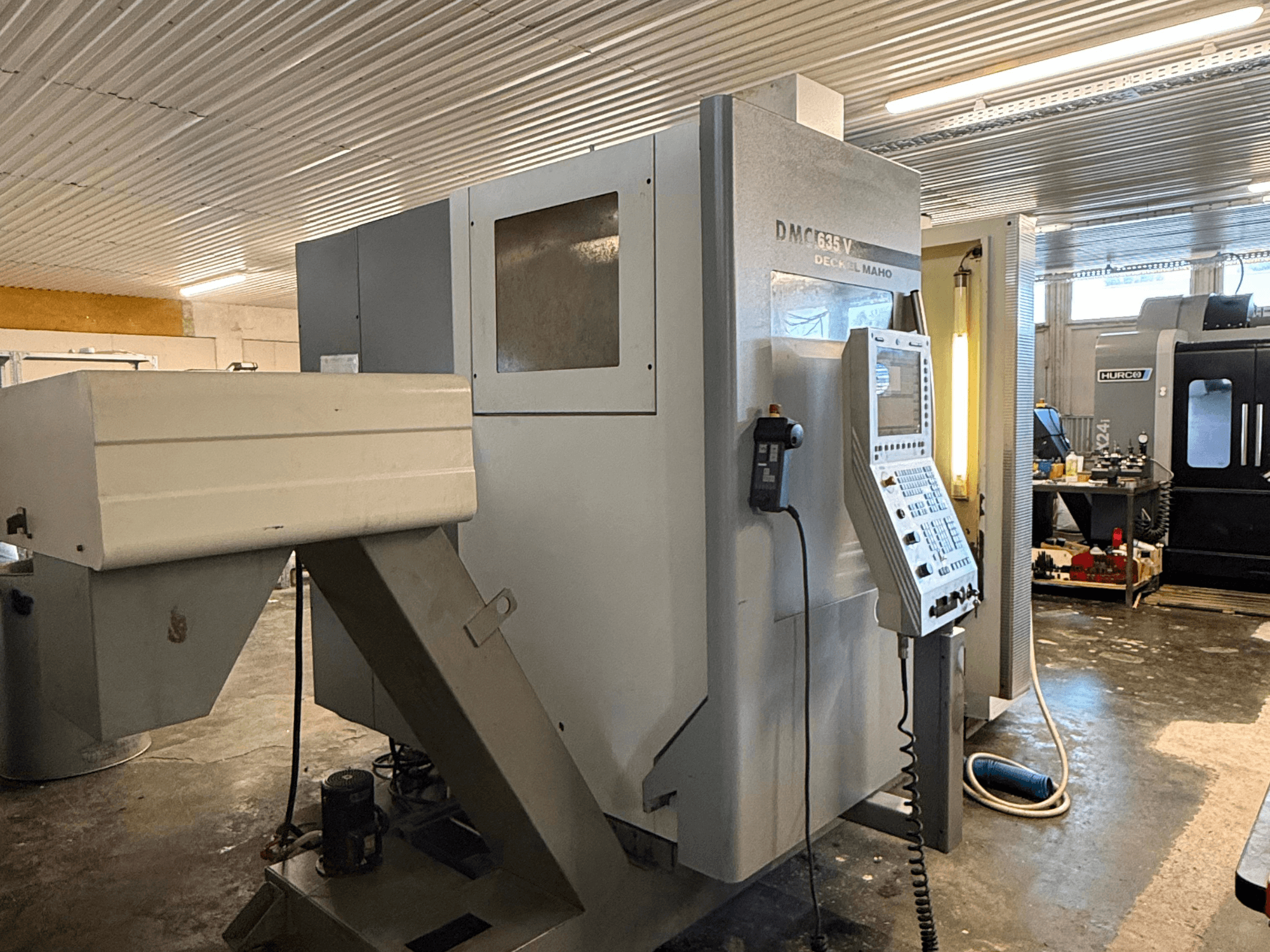 Fresatrice DMC G635V in un'officina, vista frontale con pannello di controllo e utensili collegati visibili.