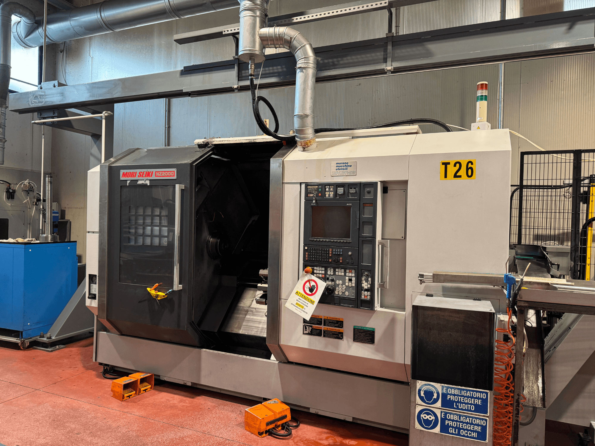 Centro di tornitura MORI SEIKI NZ-2000/T2/Y2, vista frontale, con pannello di controllo, segnaletica di sicurezza e allestimento industriale.