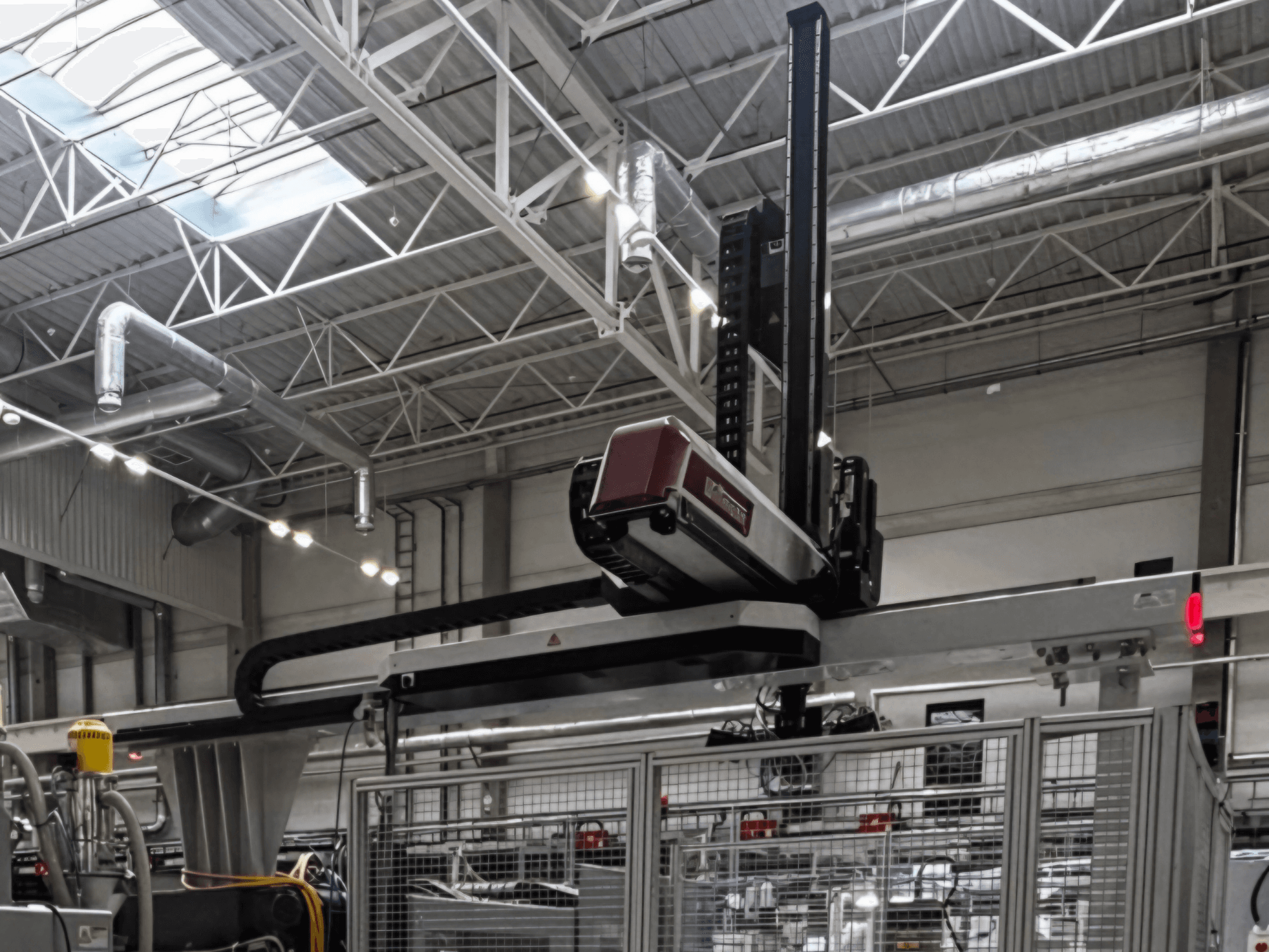 Macchina per la lavorazione della plastica WITTMANN W832PRO in un ambiente industriale, vista laterale che mostra il sistema sospeso e lo sfondo industriale.