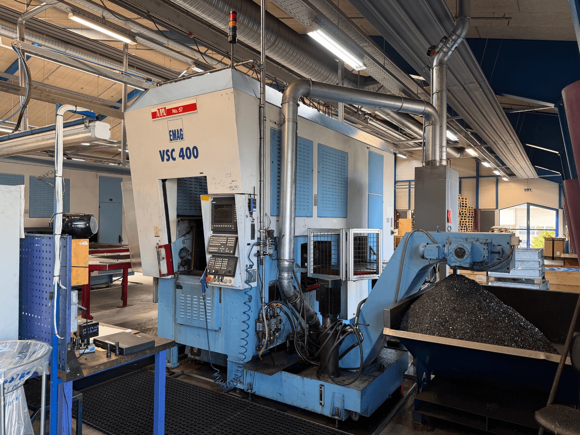 Tornio verticale EMAG VSC 400, vista frontale, con pannello di controllo e convogliatore di trucioli. Ambientazione industriale visibile.