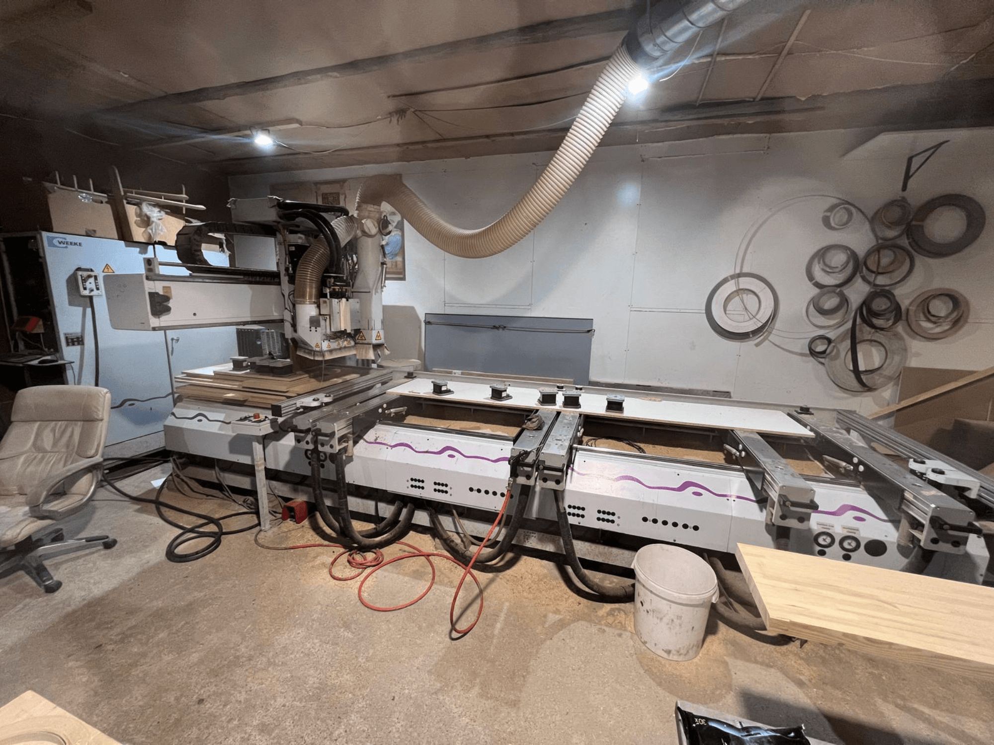 Centro di lavorazione del legno a controllo numerico Weeke OPTIMAT BP 120 in officina, vista frontale con pezzi di legno e utensili visibili sulla superficie.