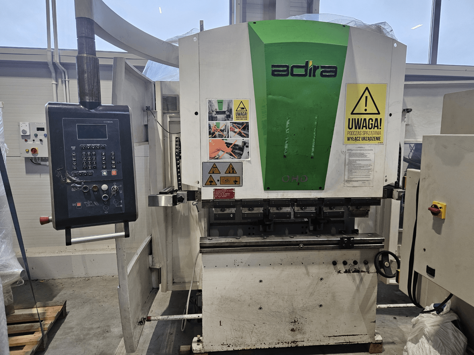 Macchina Adira OHD vista frontalmente, con pannello di controllo, avvisi di sicurezza e pulsanti operativi.