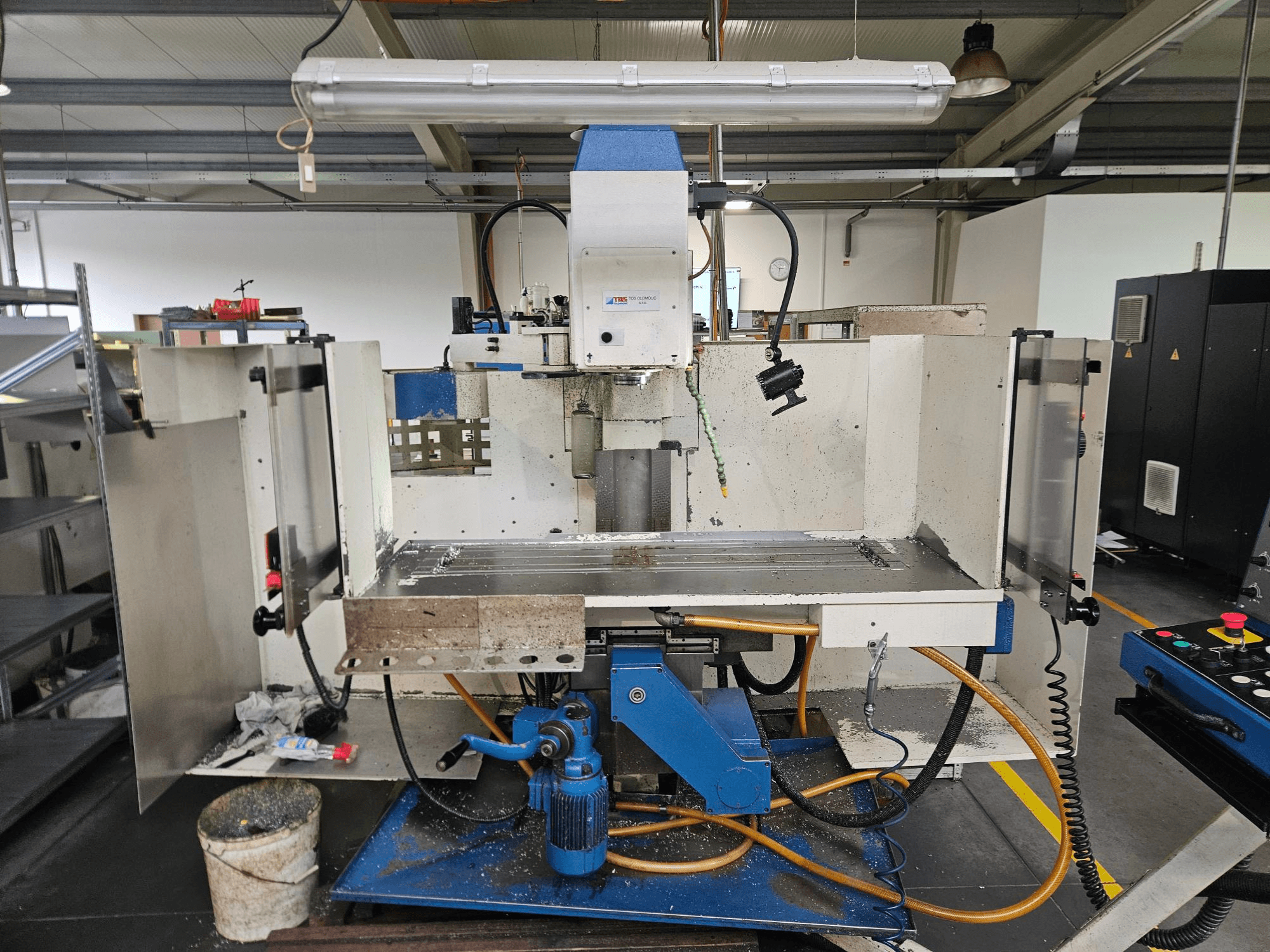 TOS Olomouc FV30 CNC Un centro di lavoro verticale in un'officina, vista frontale che mostra il pannello di controllo, il piano di lavoro e il sistema di raffreddamento.