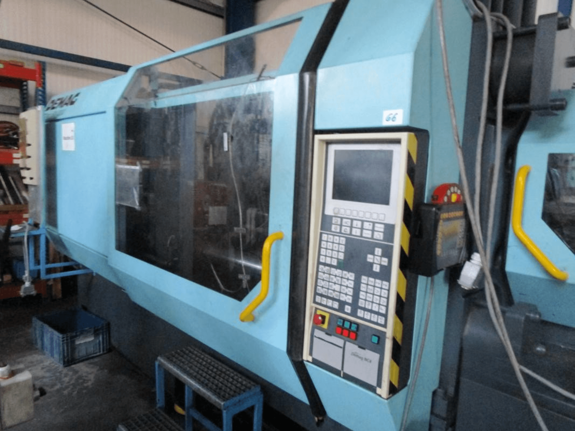 Pressa a iniezione idraulica Demag Erdotech 500-3300, vista frontale, con pannello di controllo e involucro di sicurezza trasparente.