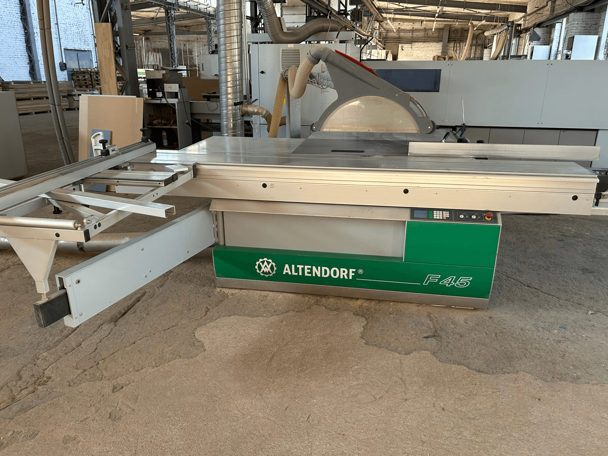 Sega per pannelli Altendorf F 45, vista frontale, che mostra il piano di taglio, la protezione della lama e il pannello di controllo sulla macchina di colore verde e grigio.