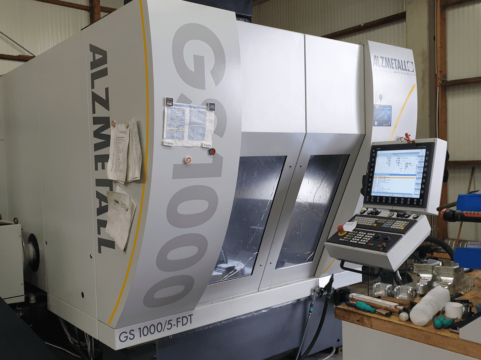 Centro di lavorazione verticale Alzmetall GS 1000/5-FDT visto frontalmente, con in primo piano il pannello di controllo e l'area di lavoro.