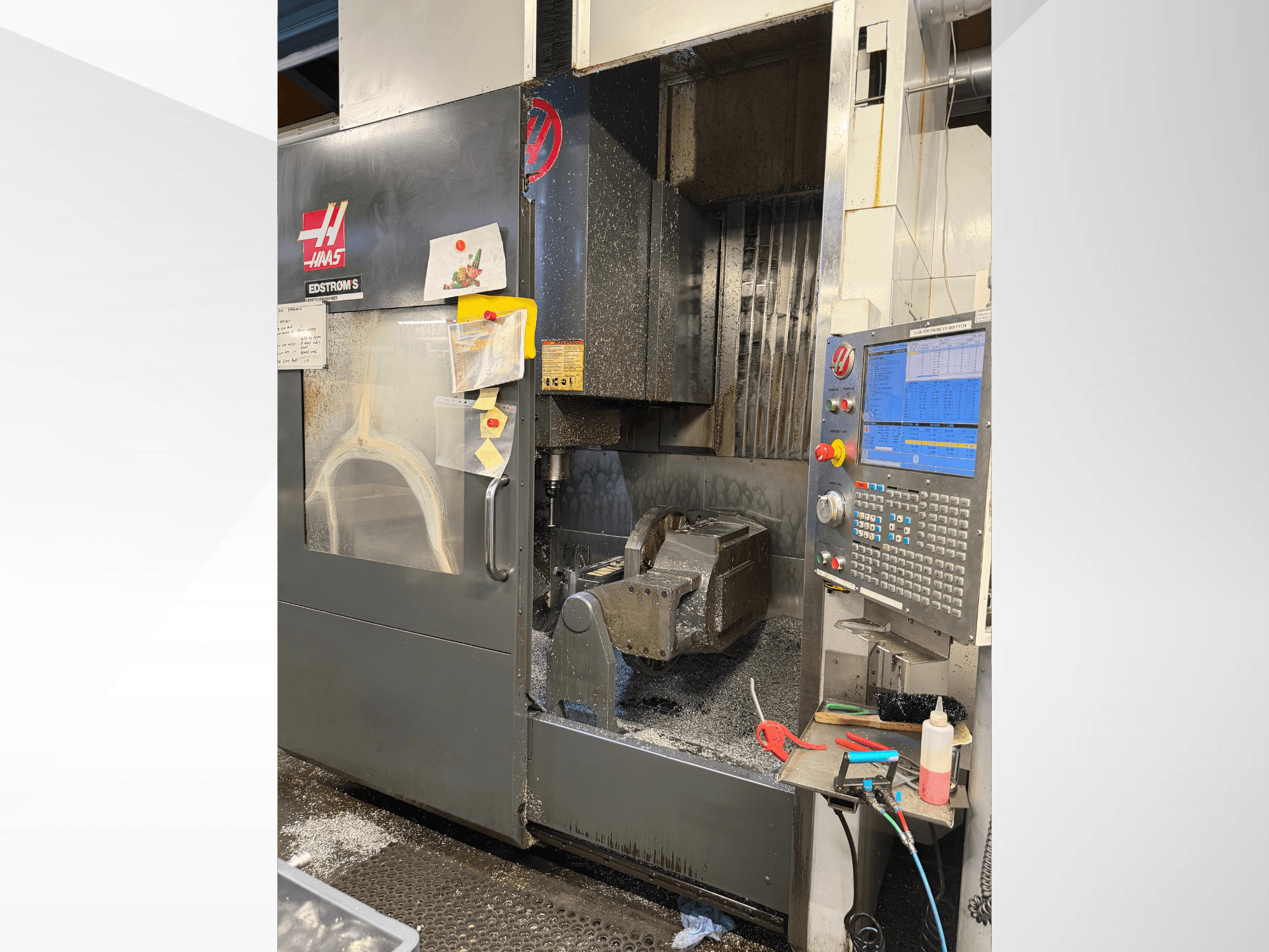 Macchina CNC Haas modello EDSTROM S, vista frontale, con pezzo in metallo, pannello di controllo e trucioli di metallo all'interno.
