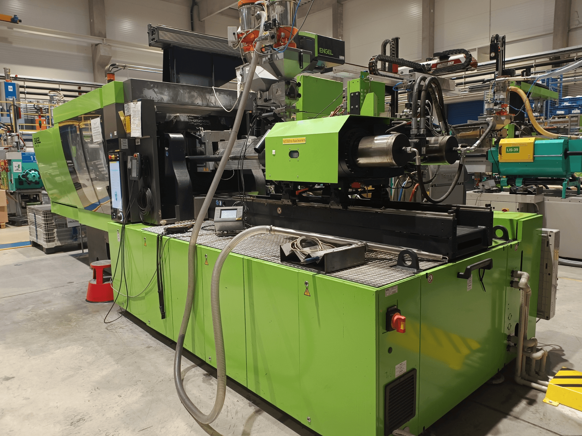 Macchina ad iniezione Engel, vista laterale, esterno verde, con pannello touchscreen e componenti idraulici visibili.
