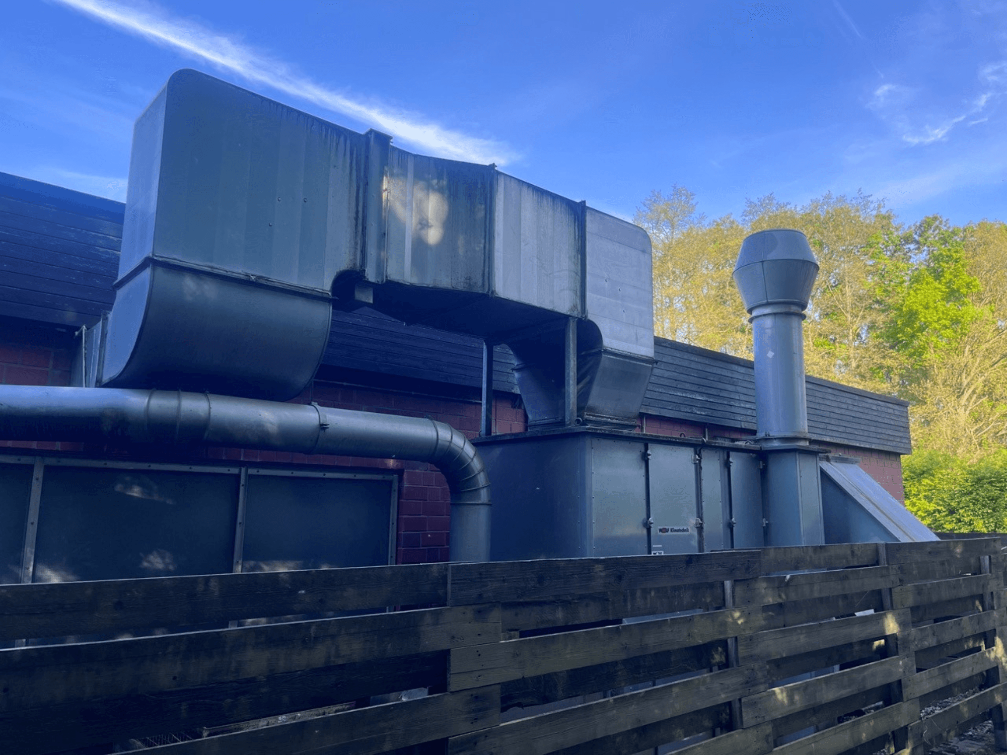 Sistema di ventilazione industriale con condotti metallici, vista laterale; comprende un camino quadrato e uno cilindrico, finitura verde.