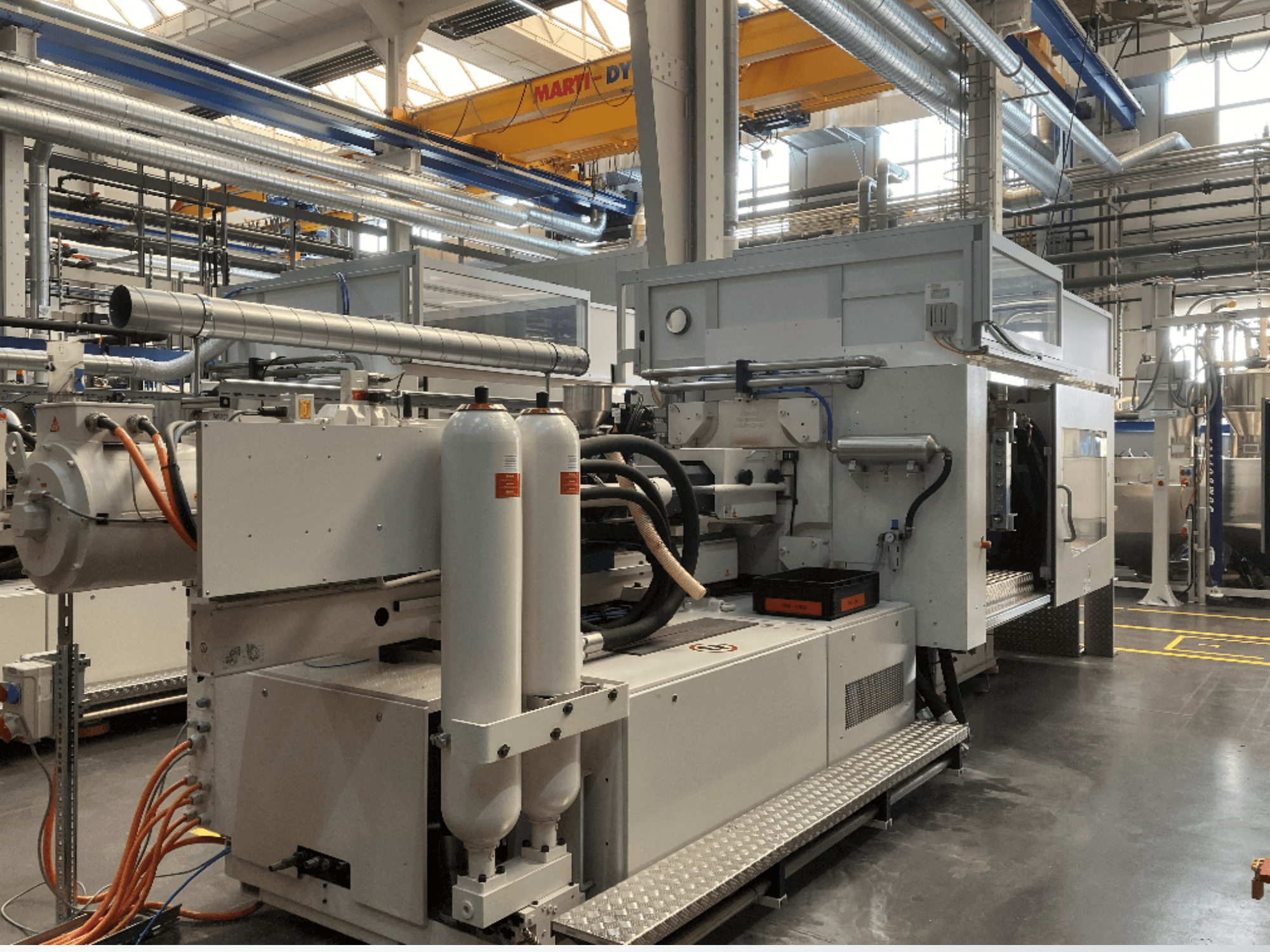 Macchina industriale vista di lato con più tubi, due serbatoi verticali e pannello di controllo; marca/modello non visibile.