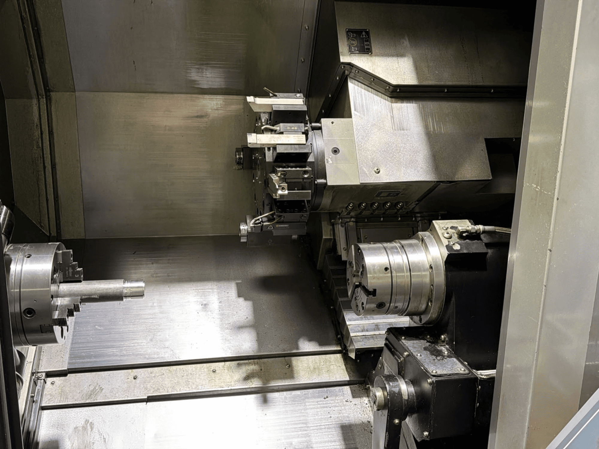 Vista interna del centro di tornitura-fresatura Hurco TMX8MYS che mostra il mandrino, il mandrino di serraggio e il portautensili con superfici metalliche.