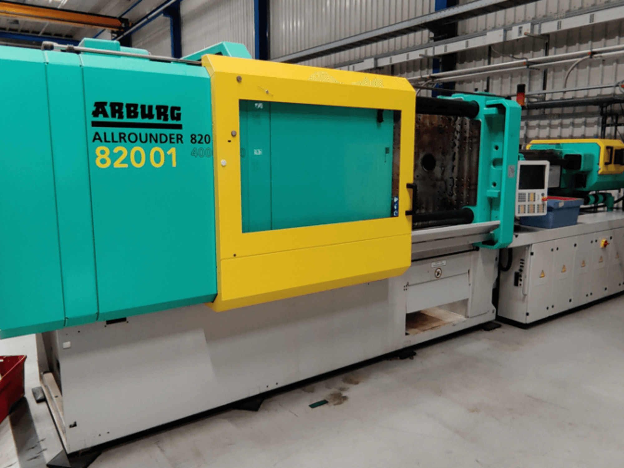 Pressa ad iniezione Arburg ALLROUNDER 82001 in colore verde e giallo, vista laterale che mostra il pannello di controllo e le caratteristiche operative.