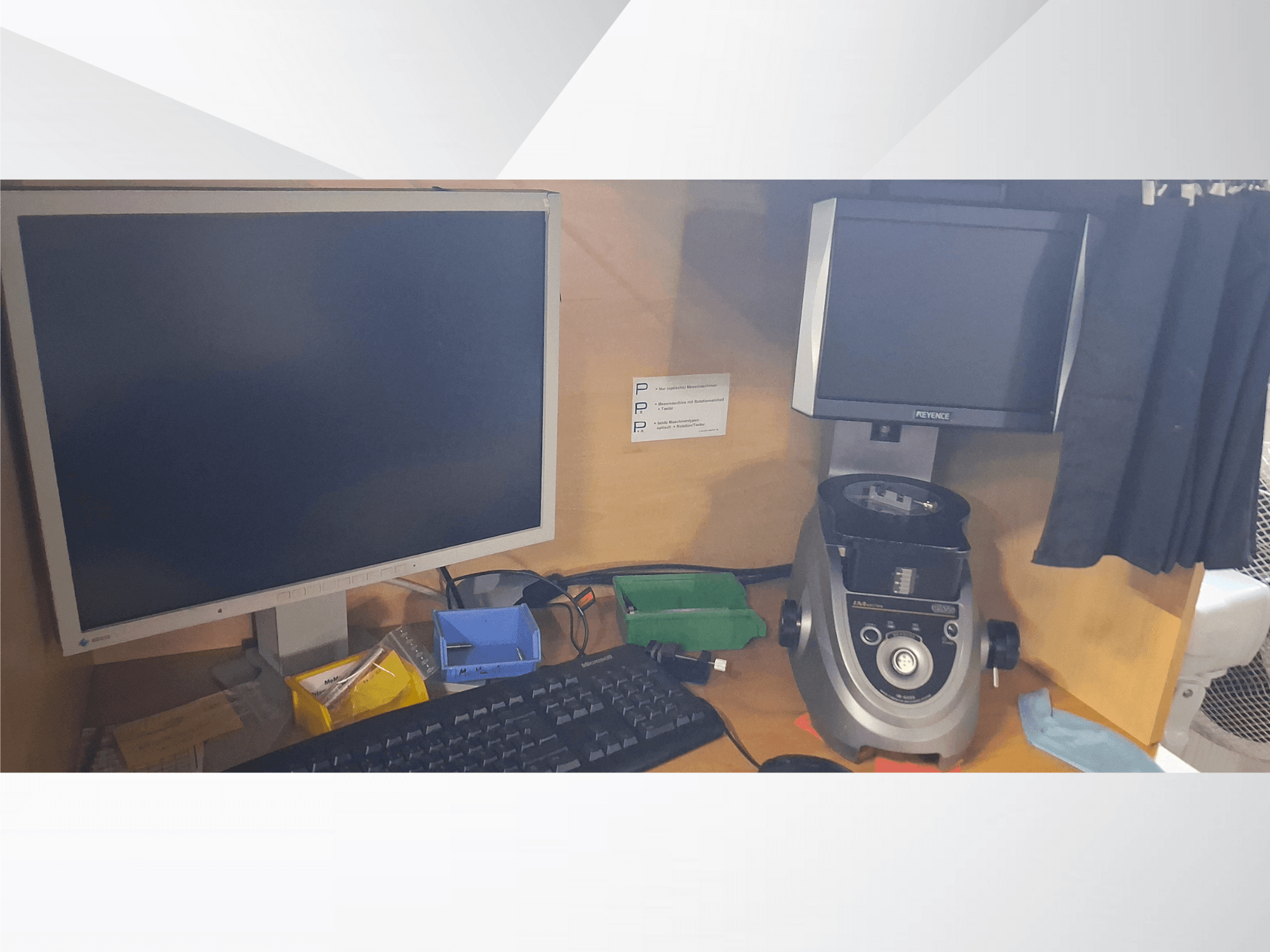 Monitor del computer con tastiera, display in PEVA e un dispositivo da laboratorio grigio su una scrivania in legno con vassoi e documenti assortiti.