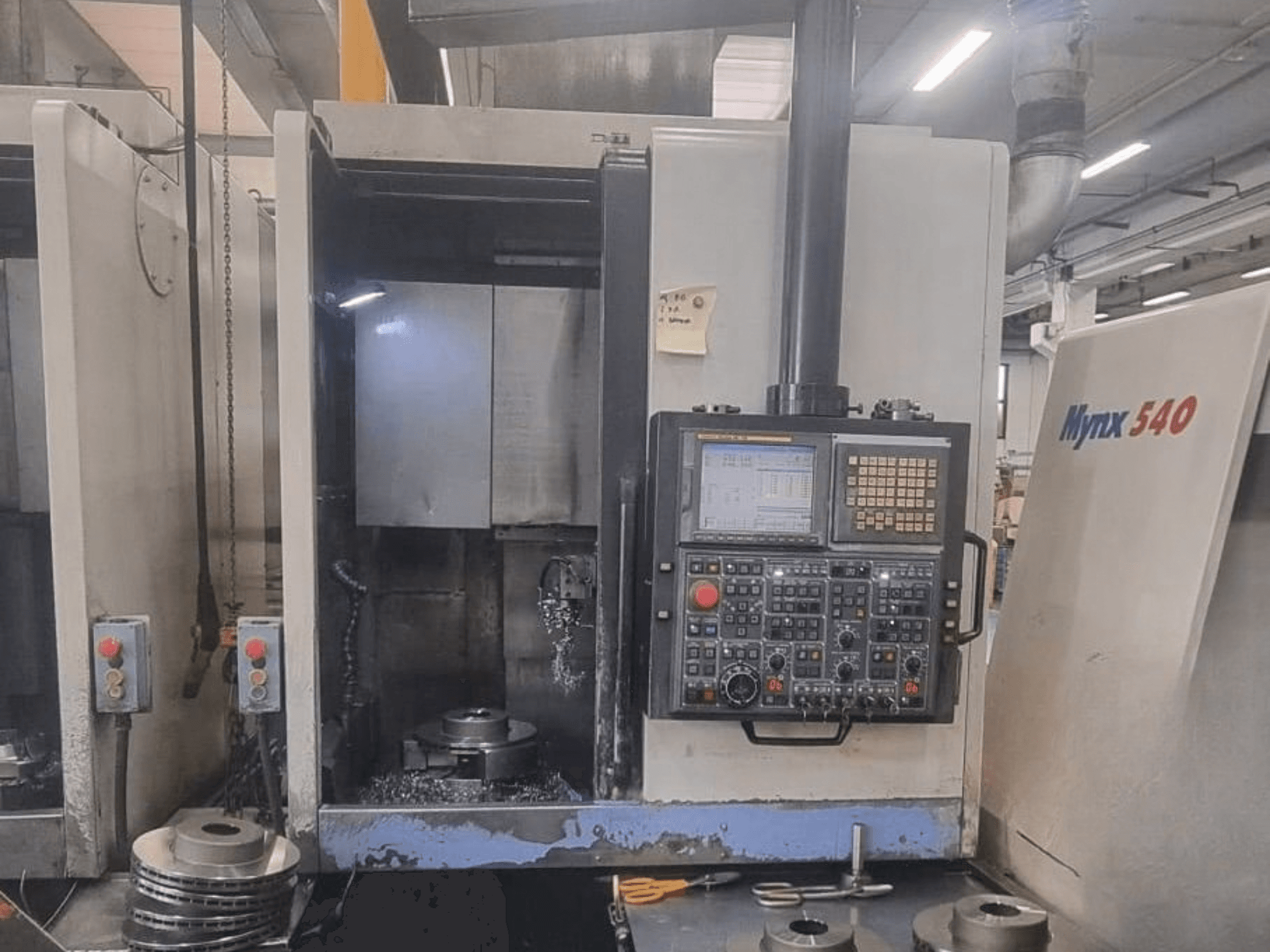 Vista frontale di un tornio verticale DOOSAN PUMA V400-2SP, che mostra il pannello di controllo e il posizionamento del pezzo all’interno della macchina.