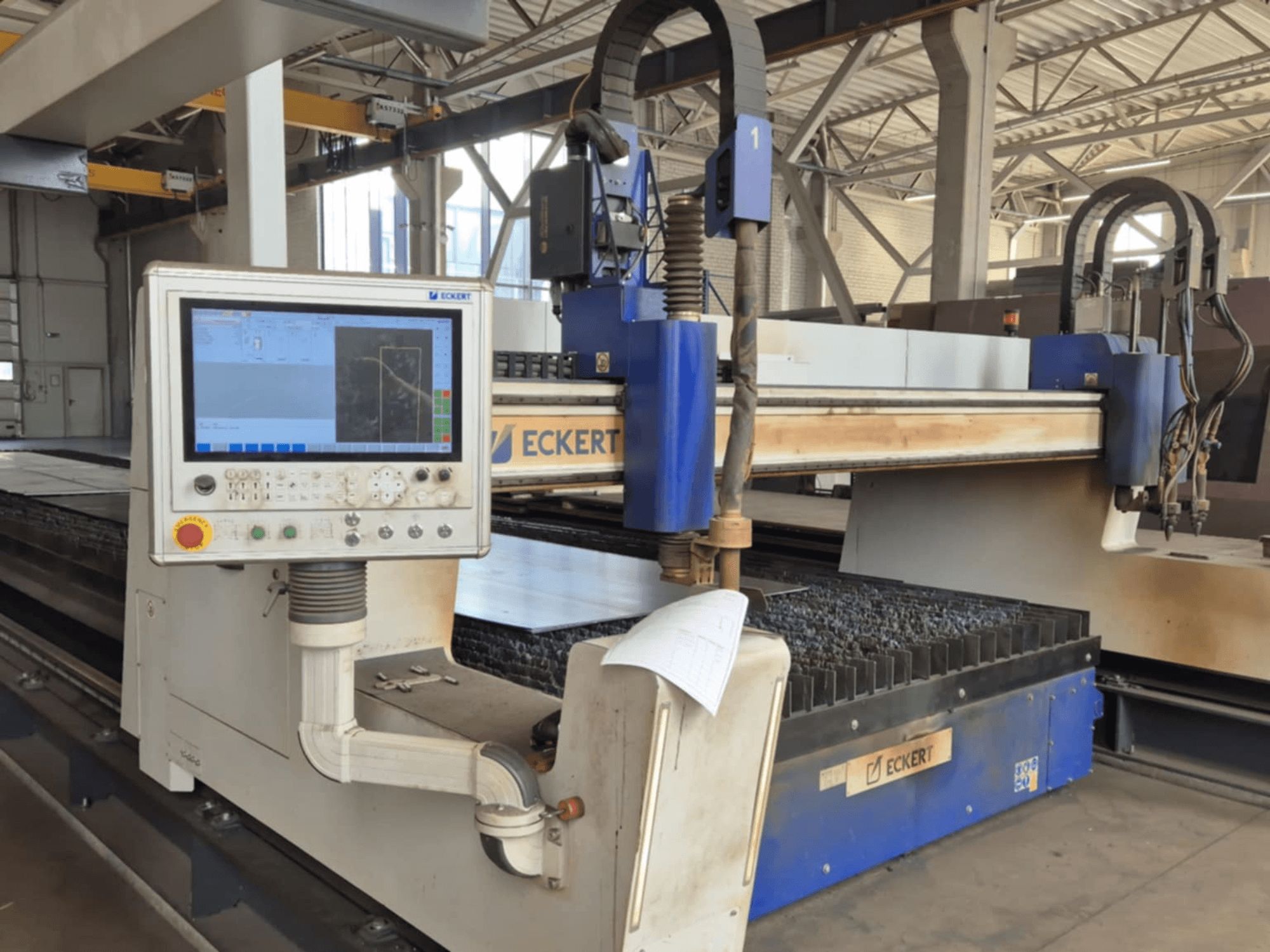 Pannello di controllo della macchina da taglio CNC ECKERT in vista frontale, con display touchscreen e vari pulsanti operativi.