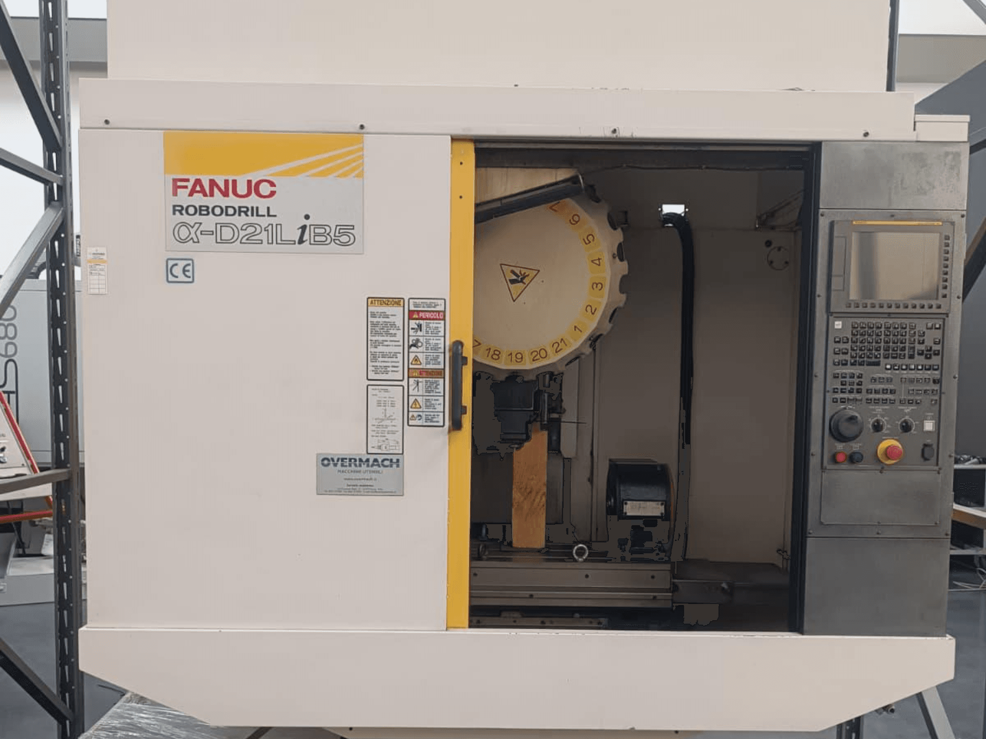 FANUC Robodrill α-D21LiB5, vista frontale; macchina CNC con portautensili, pannello di controllo e avvertenze di sicurezza visibili.