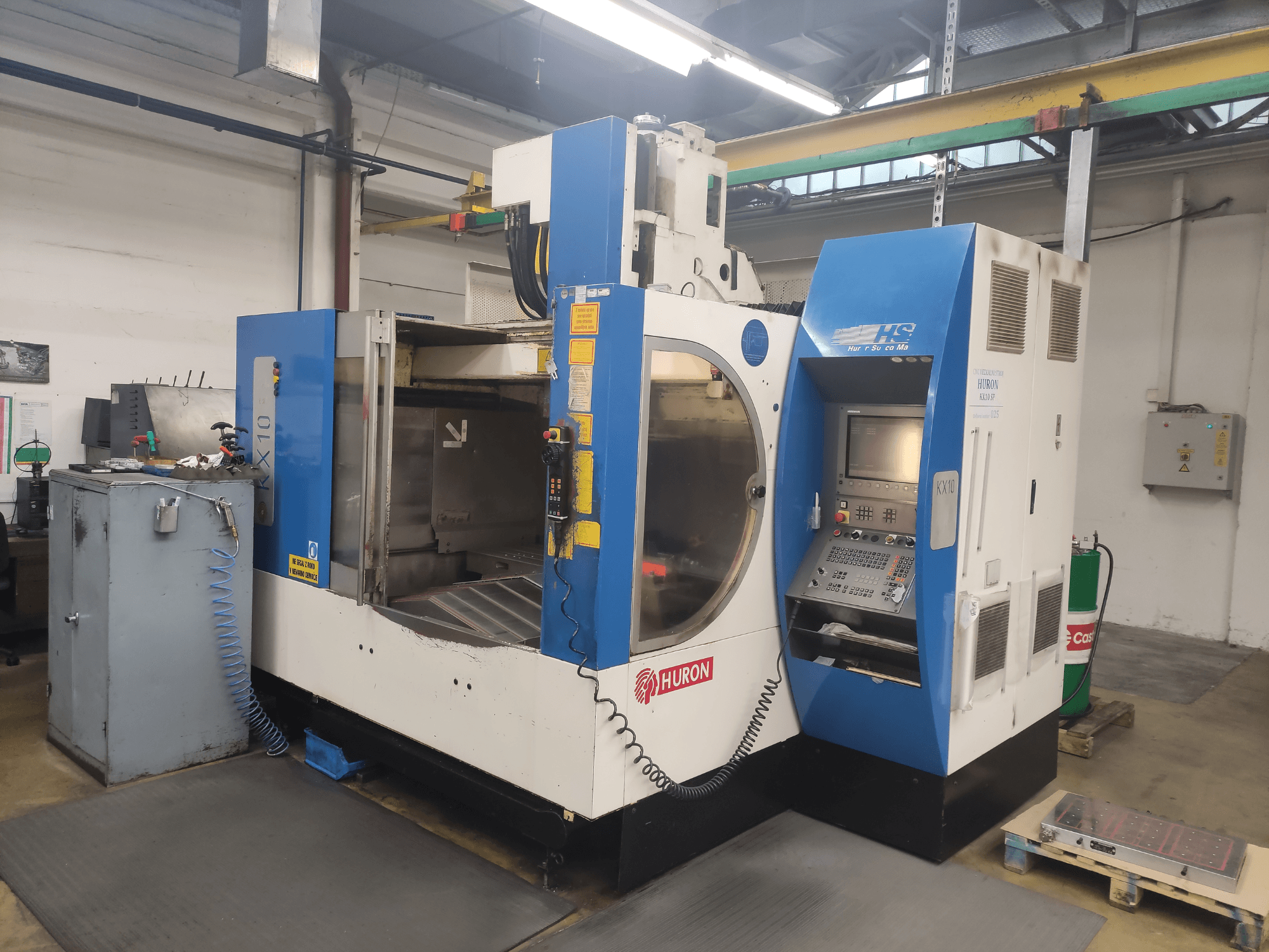 Macchina CNC HURON KX10 in un'officina, vista frontale, con pannello di controllo e ampia apertura per la lavorazione.