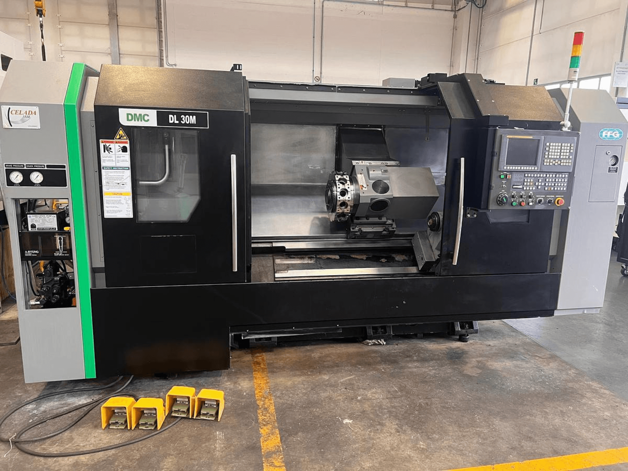 Macchina CNC DMC DL 30M con vista laterale che mostra i comandi, il mandrino e i tre pedali sul pavimento.