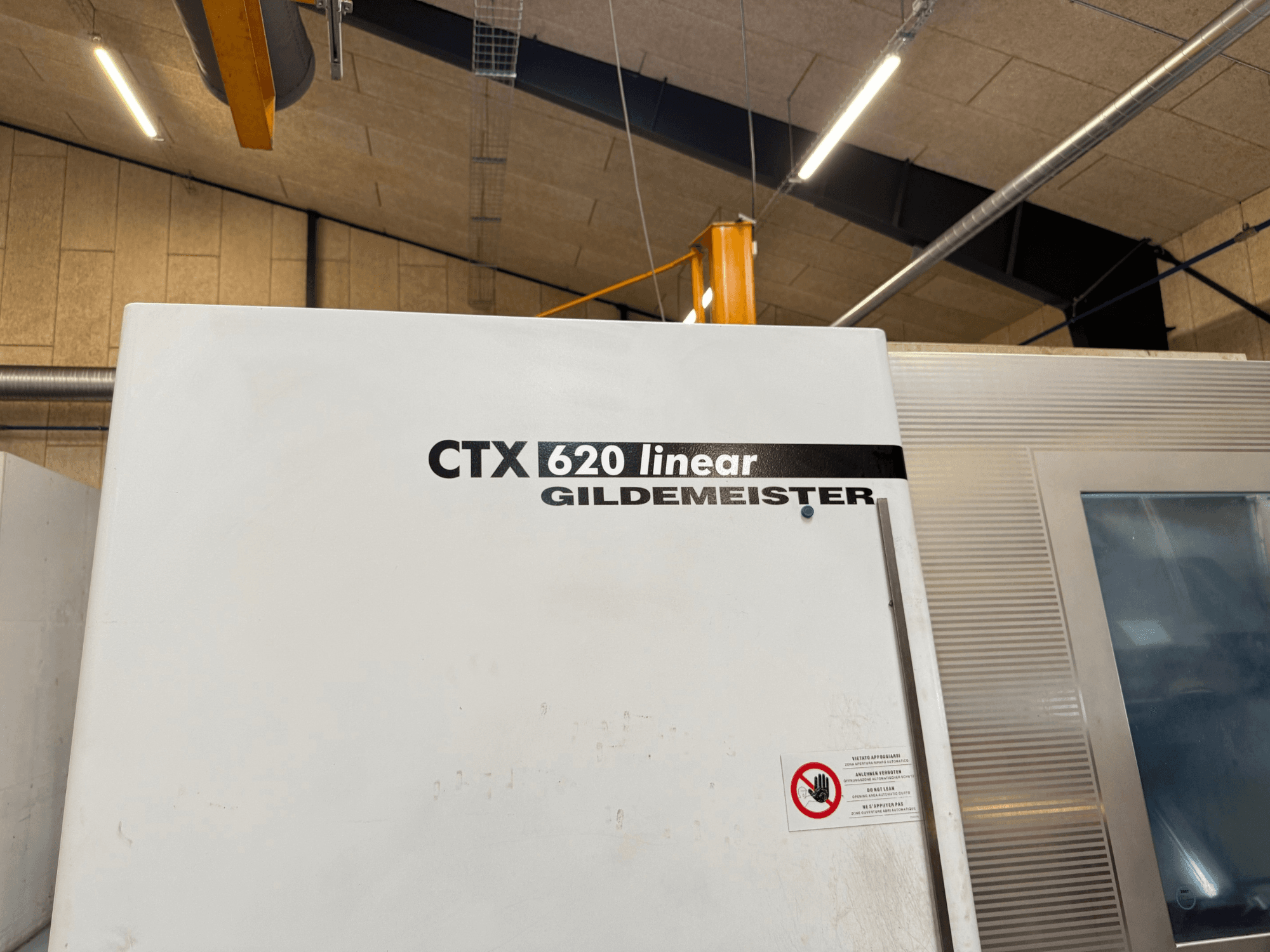 Vista laterale della macchina CTX 620 Linear Gildemeister, con esterno bianco ed etichette di sicurezza.