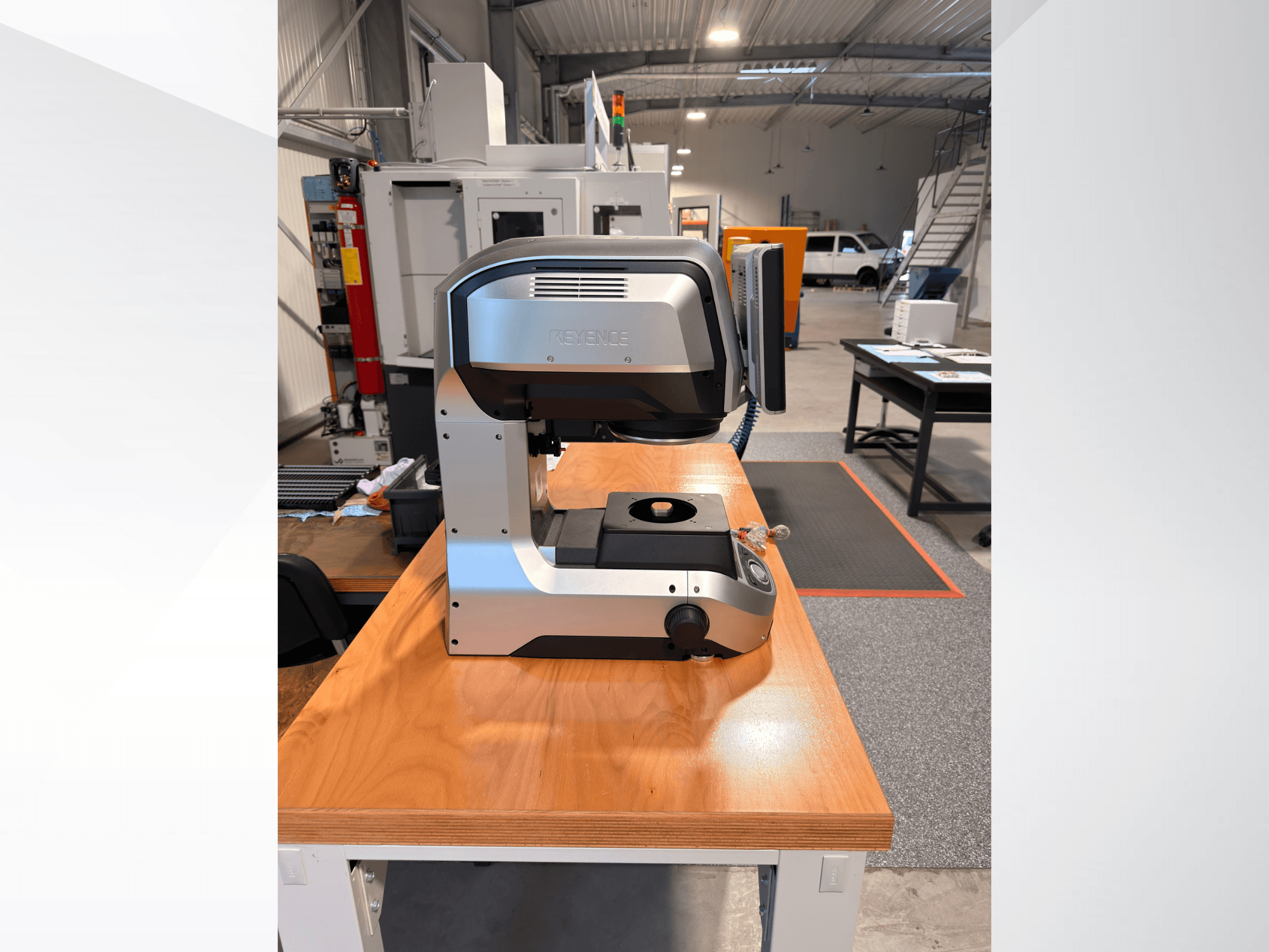 Vista frontale della macchina di misurazione ottica KEYENCE IM-8005 su un tavolo di legno, che ne mette in risalto il design elegante e l'interfaccia operativa.