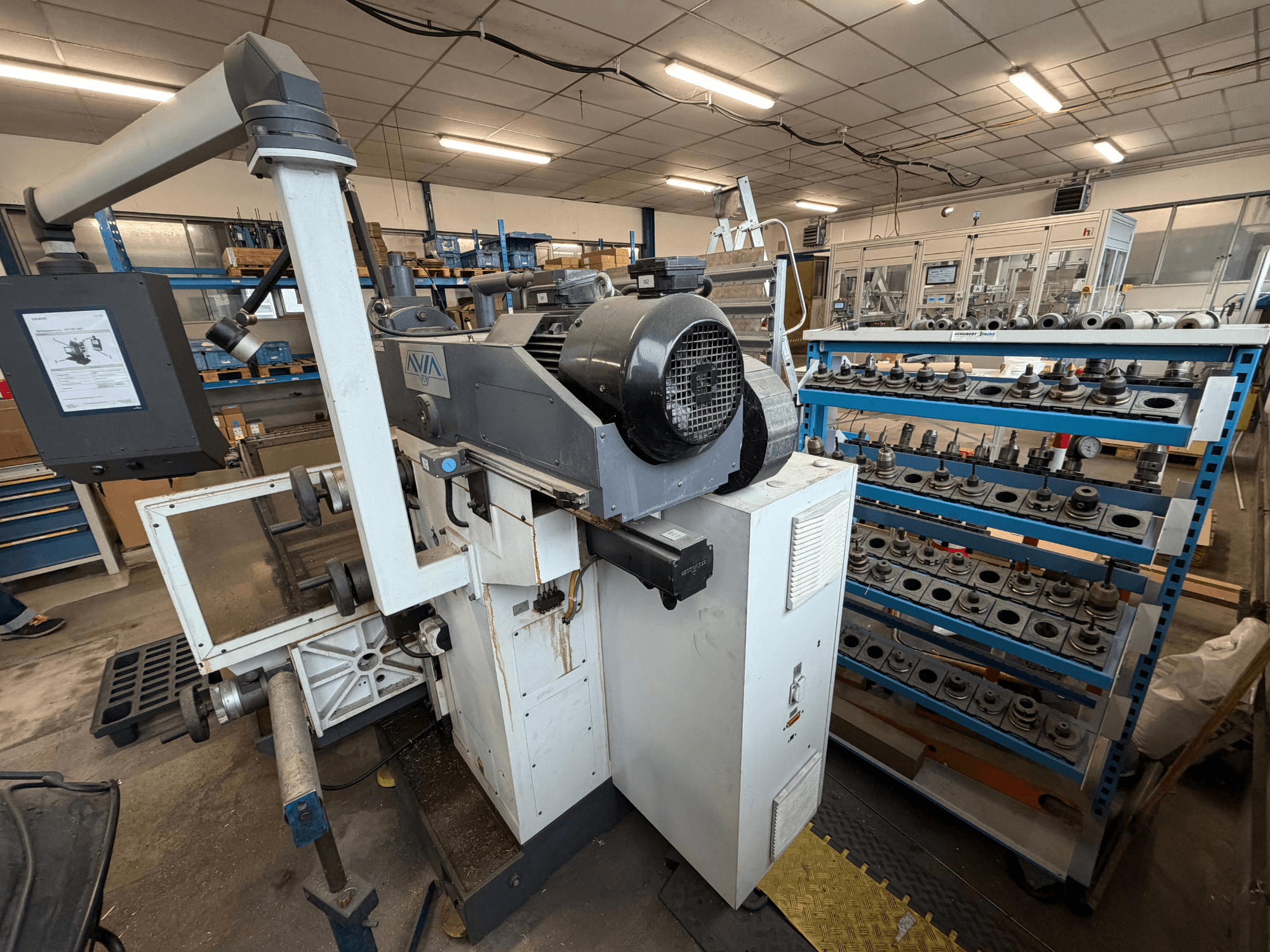 Centro di lavorazione universale Avia FNX30NC, vista frontale che mostra i comandi e l'area di stoccaggio degli utensili, con i componenti sullo sfondo.