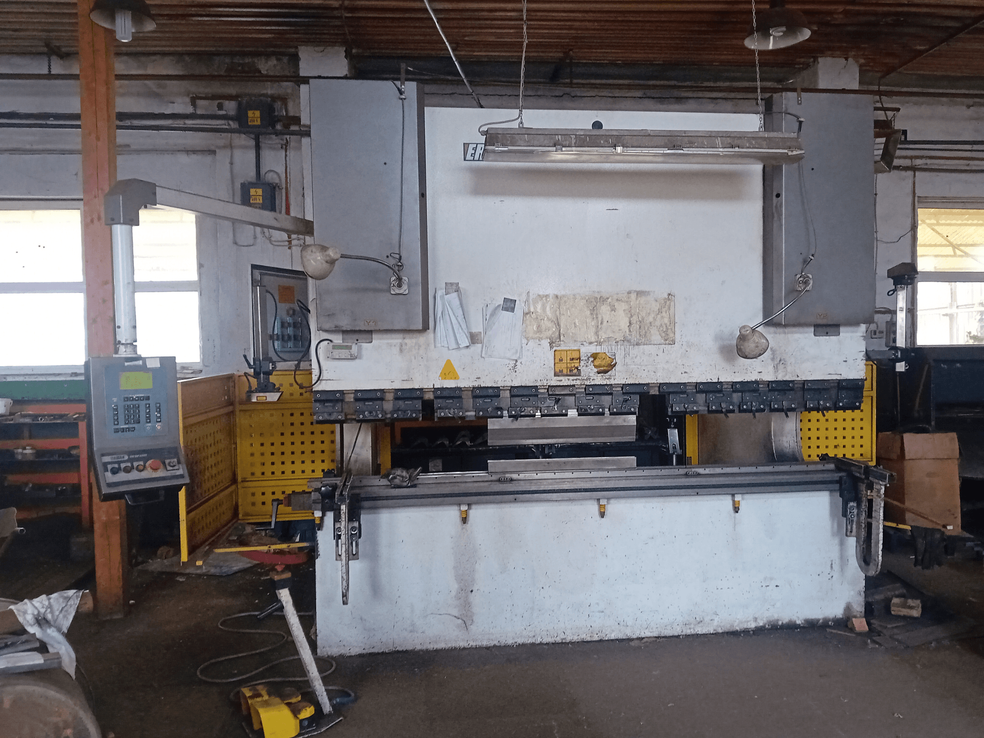 Pressa idraulica ERMAK CNC HAP 3100x300 vista di fronte, con pannello di controllo e banco di lavoro in un'officina.