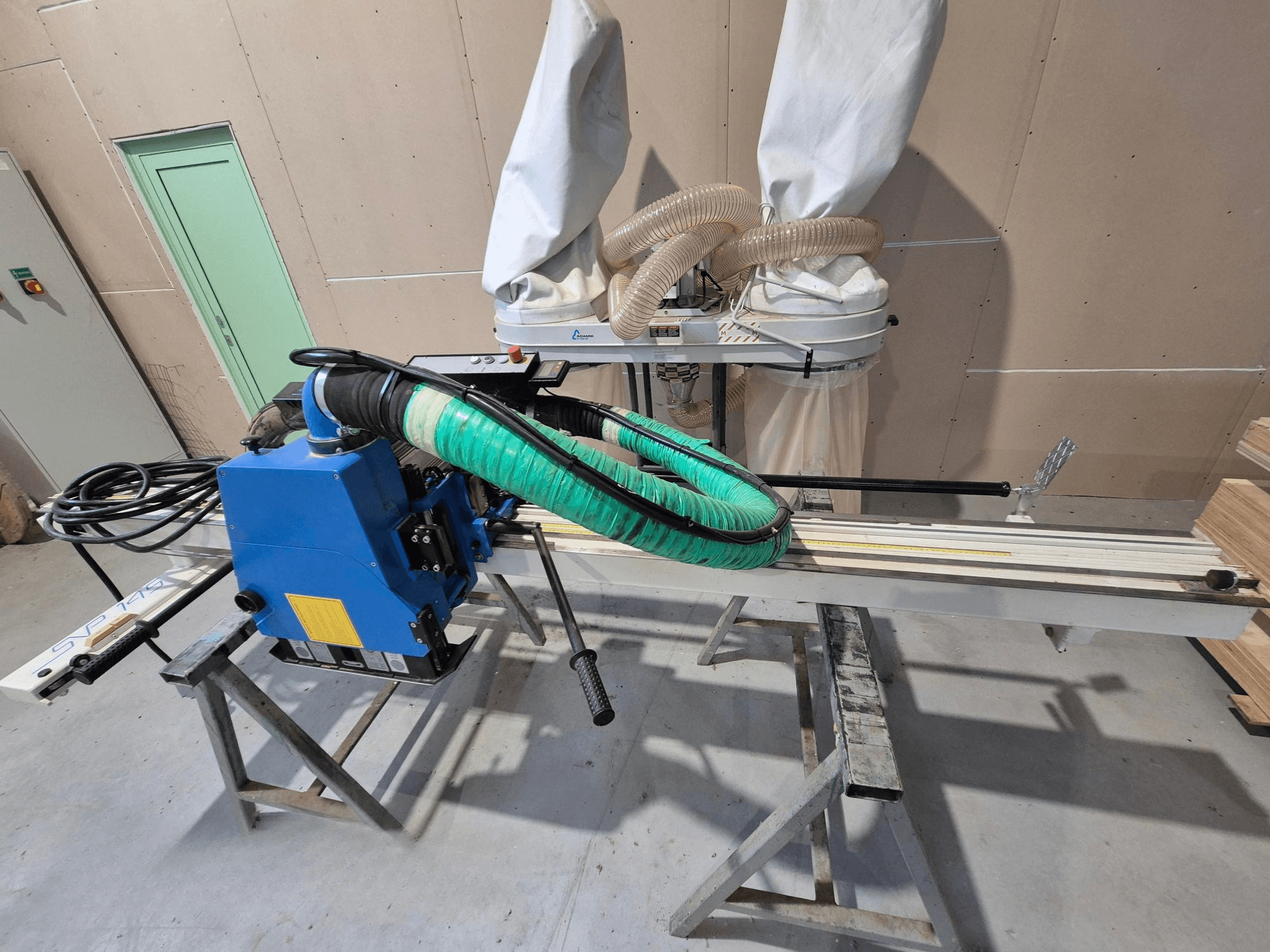 Sezionatrice orizzontale SVP-175 blu con tubo flessibile per la polvere e supporto verde, vista di lato in un'officina.