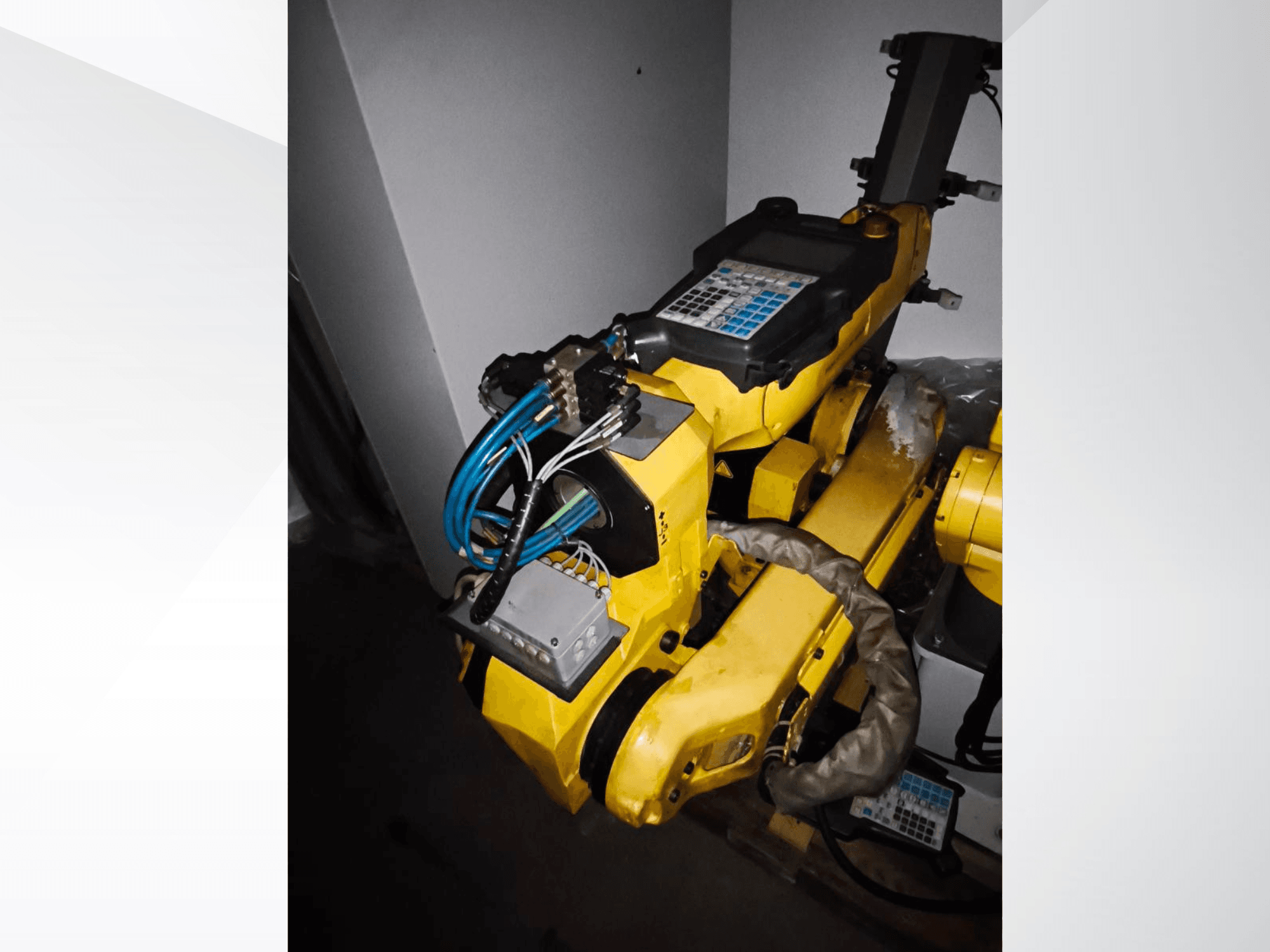 Braccio robotico FANUC M-20iA in una vista laterale, che mostra il corpo giallo, il pannello di controllo e il cablaggio collegato.