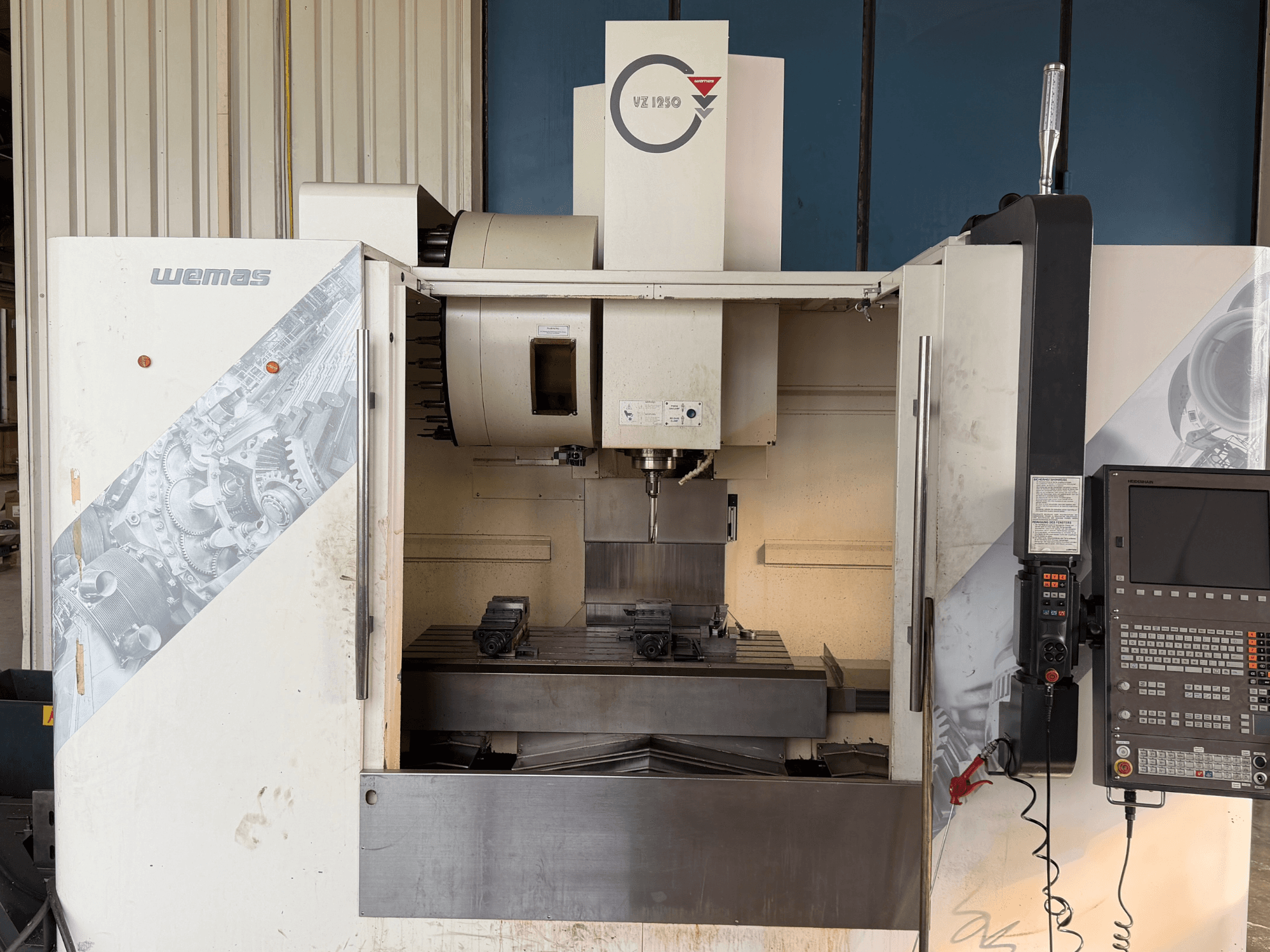 Centro di lavorazione verticale WEMAS VZ 1250, vista frontale, che mostra il pannello di comando, il mandrino e i dispositivi di fissaggio del pezzo sul basamento.