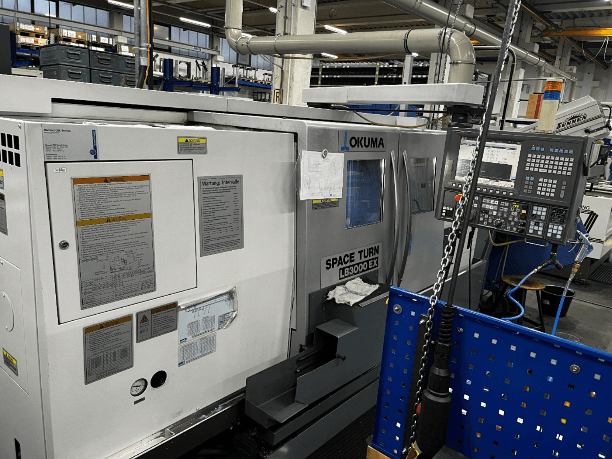 Tornio orizzontale Okuma LB3000 EX, vista frontale, con pannello di controllo e informazioni di sicurezza sul lato.