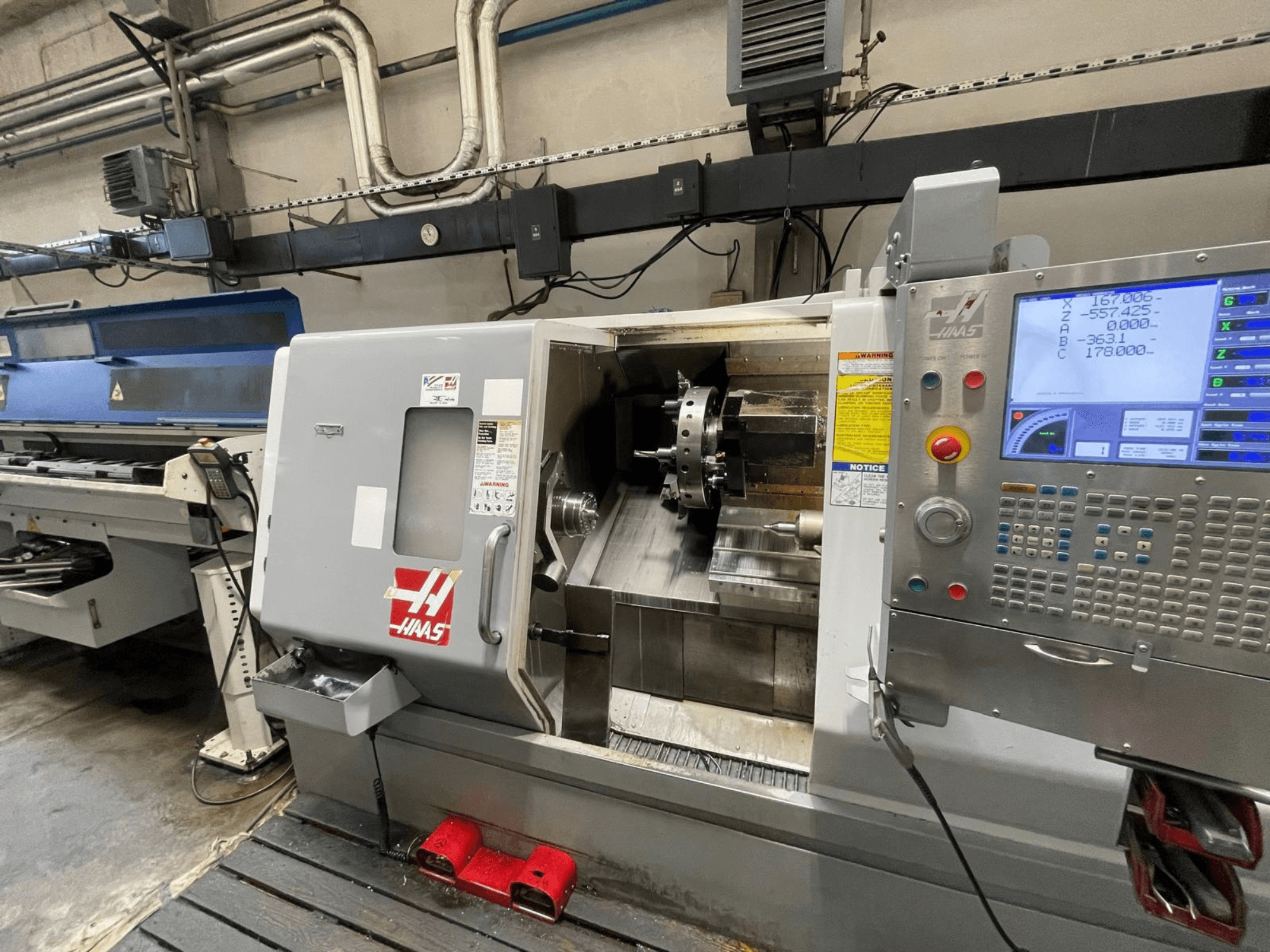 Il tornio orizzontale Haas SL-30THE in un'officina, dotato di pannello di controllo digitale e area di lavoro a vista.