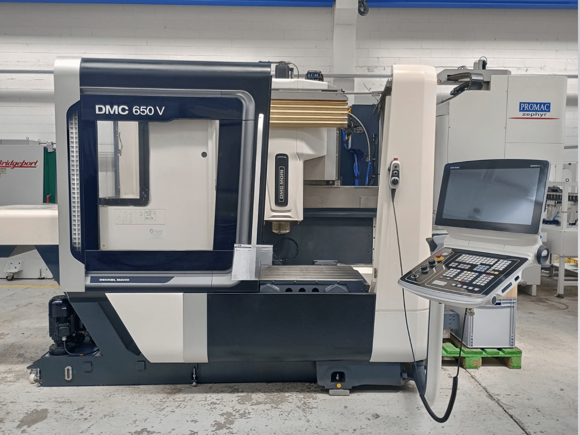 Vista laterale della macchina CNC Decker Maho DMC 650 V, con pannello di controllo con pulsanti e schermo, in un ambiente industriale.