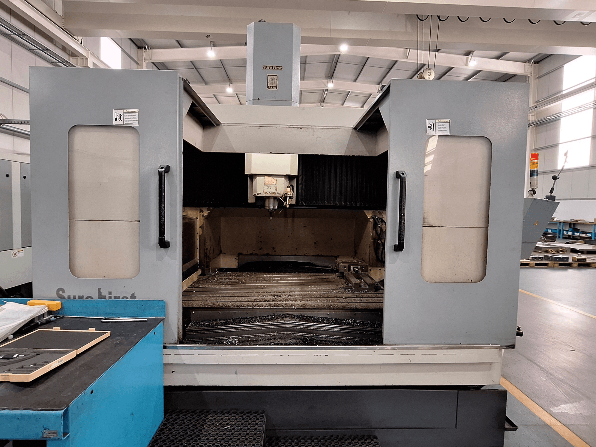 Centro di lavoro verticale Sure First QM-1836, vista frontale che mostra la testa dell'utensile e l'area di lavoro vuota, ambiente industriale moderno.