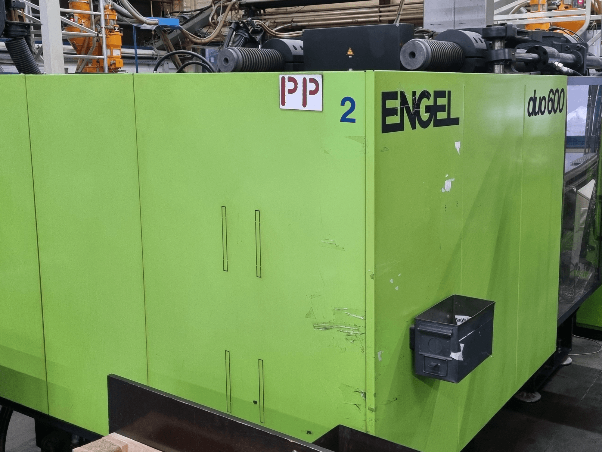 Macchina per stampaggio a iniezione idraulica Engel Duo 600, colore verde, vista frontale, con parti contrassegnate e contenitore per il materiale.