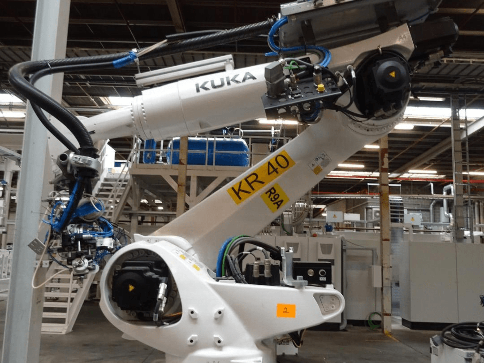 Braccio robotico KUKA KR 120 R3100-2 in vista laterale, con pannello di controllo e componenti meccanici, in un ambiente industriale.
