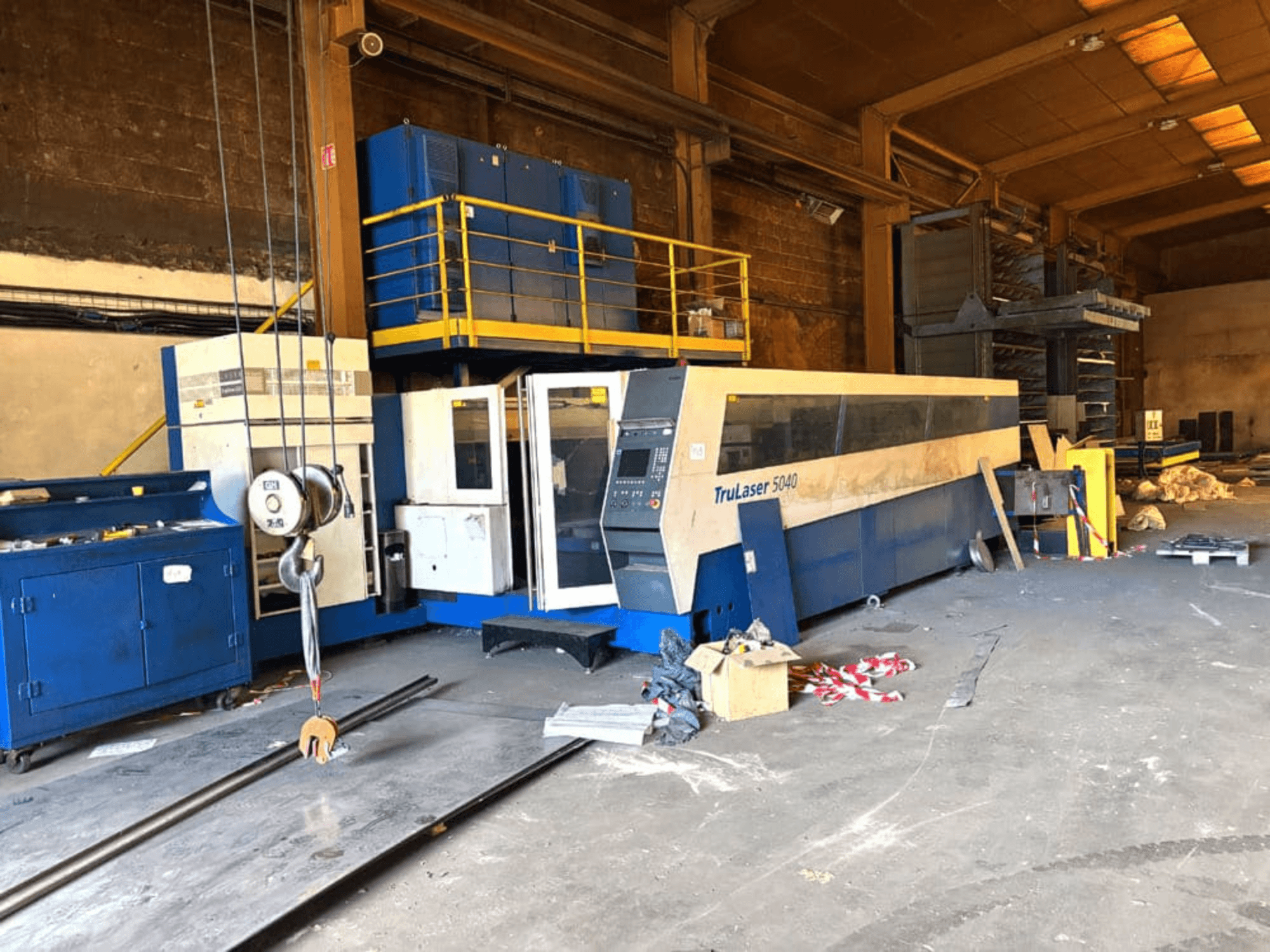 Macchina per il taglio laser a CO₂ della TRUMPF, modello TRULASER 5040, ripresa in un'officina, vista frontale obliqua con sfondo disordinato.