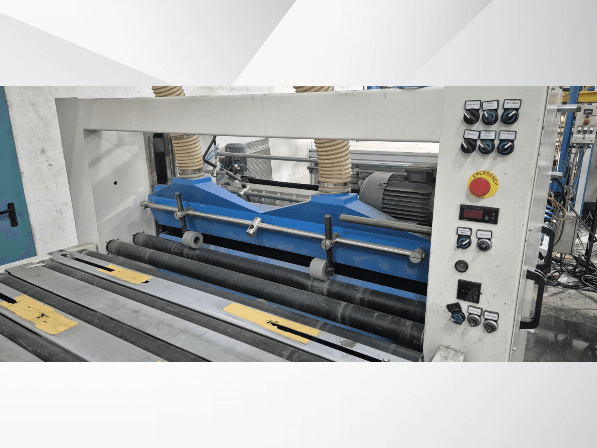 Macchina di laminazione industriale con componenti blu, vista frontale, con pannello di controllo e pulsante di arresto di emergenza.